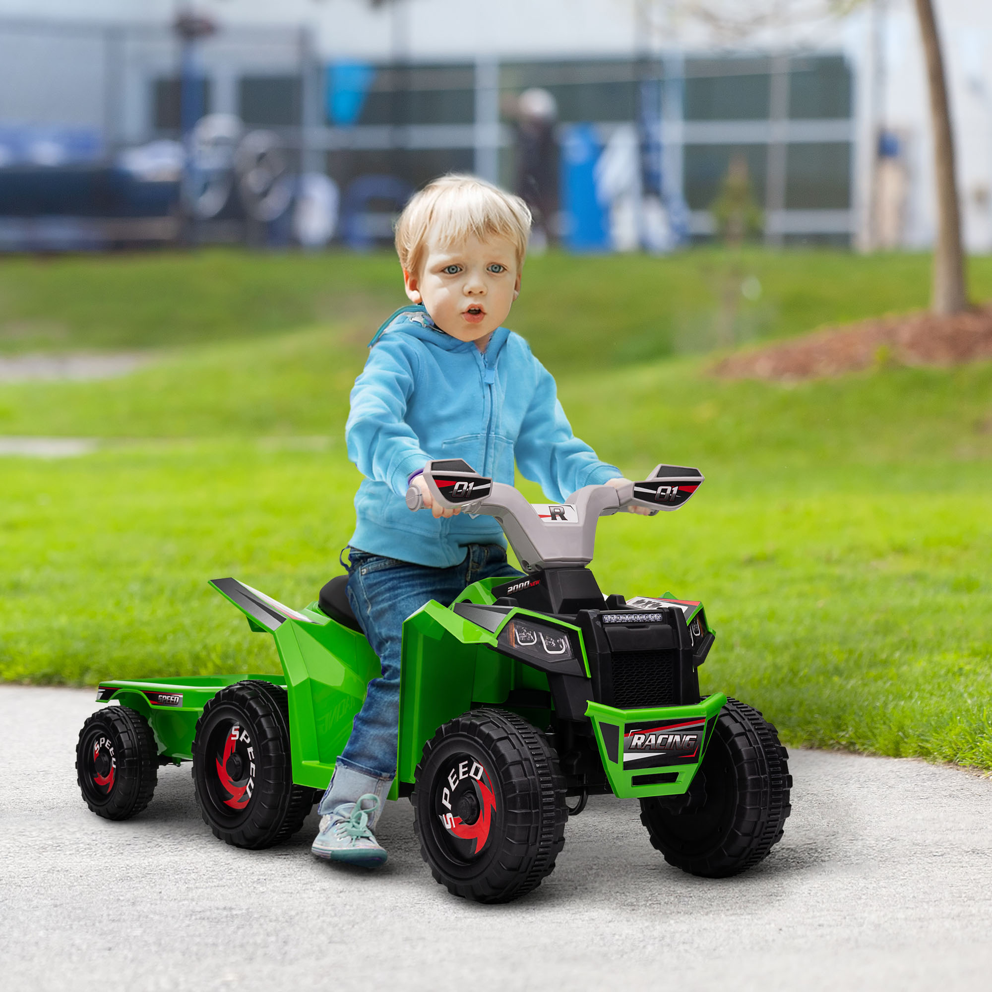 Un niño pequeño montando un juguete ATV verde y negro en un camino pavimentado.