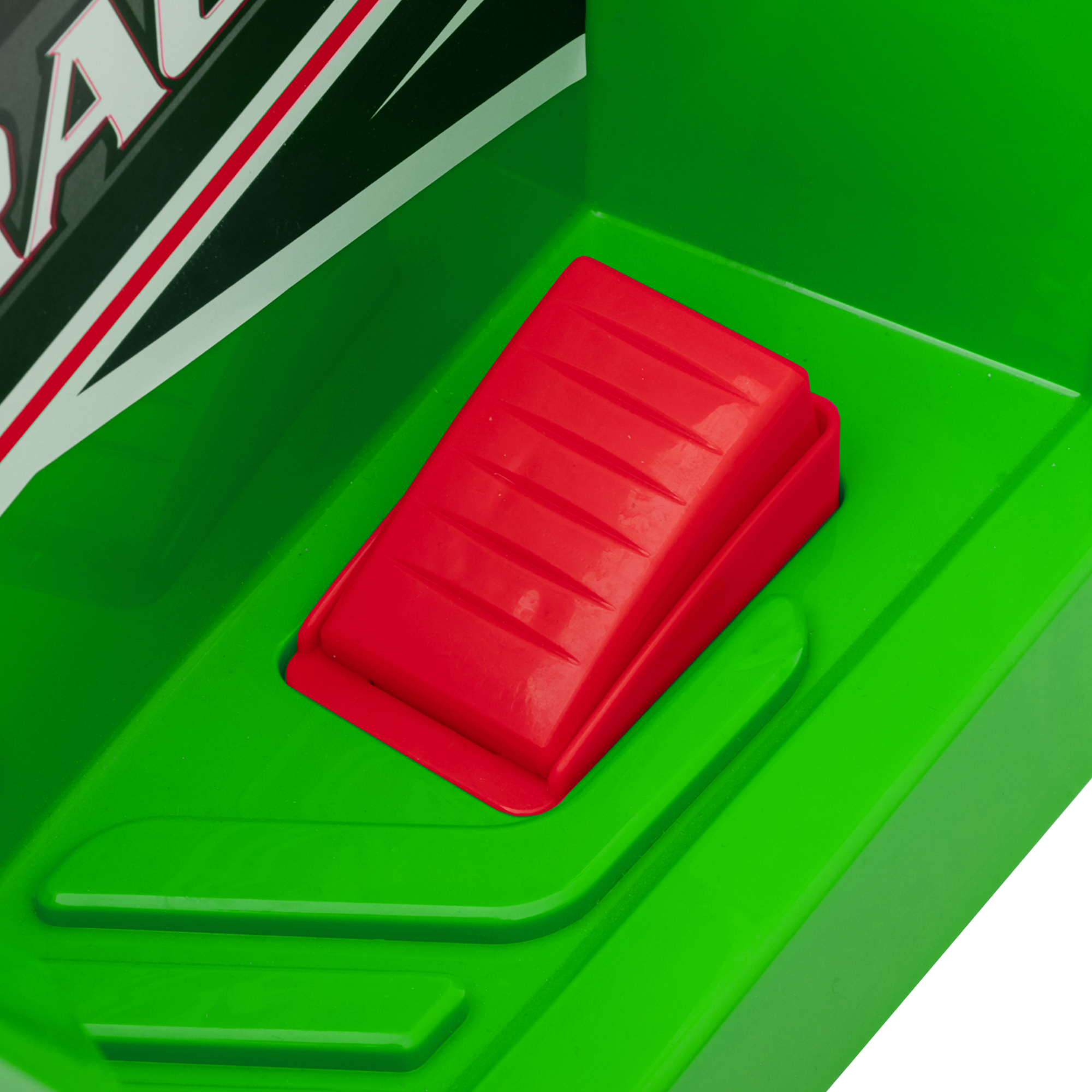 Primo piano di un pulsante rosso su un giocattolo verde. Il pulsante è rettangolare e leggermente rialzato.
