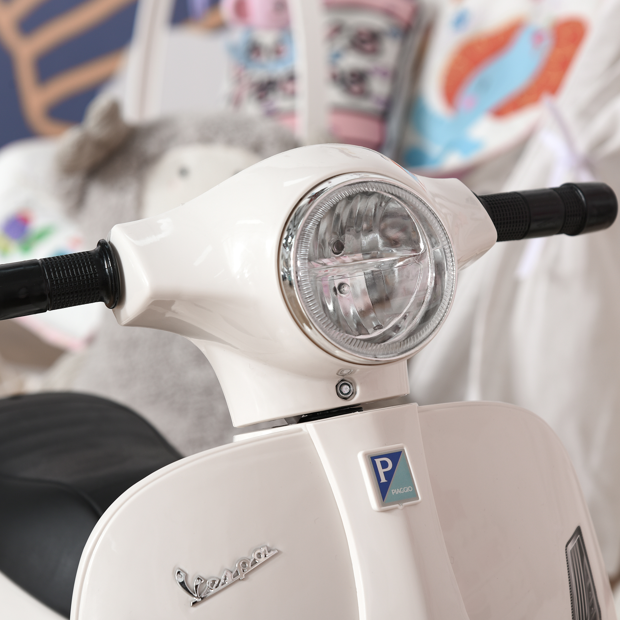 Giocattolo scooter bianco stile Vespa. La vista frontale mostra faro e manubrio.