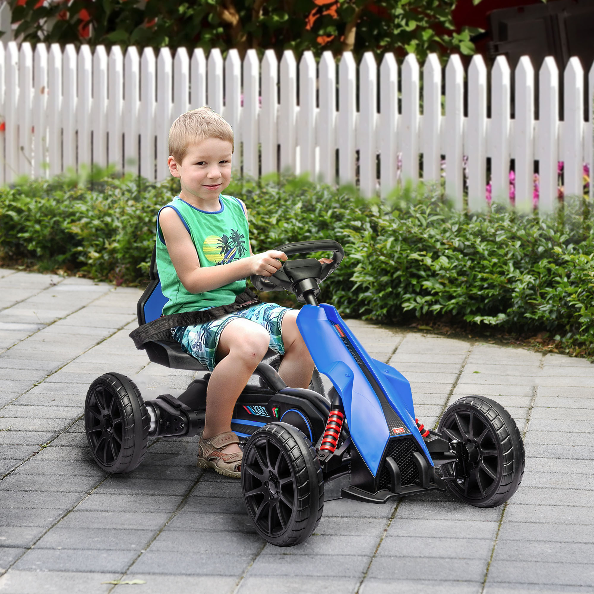 Niño en un kart azul. Valla blanca y vegetación al fondo.