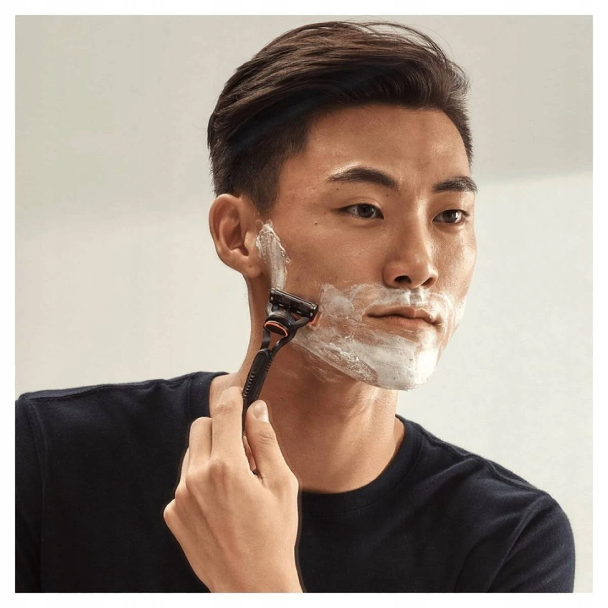 Uomo che si rade il viso con un rasoio, applicando crema da barba.