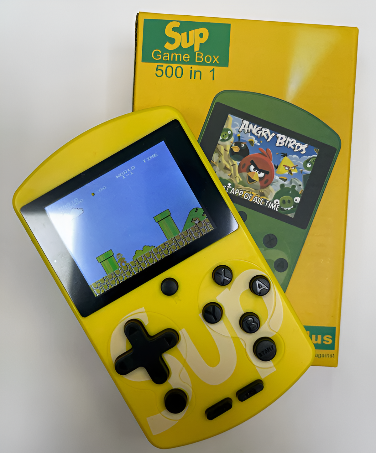 Consola de juegos portátil amarilla jugando a un juego de Mario. Juego Angry Birds en la caja.