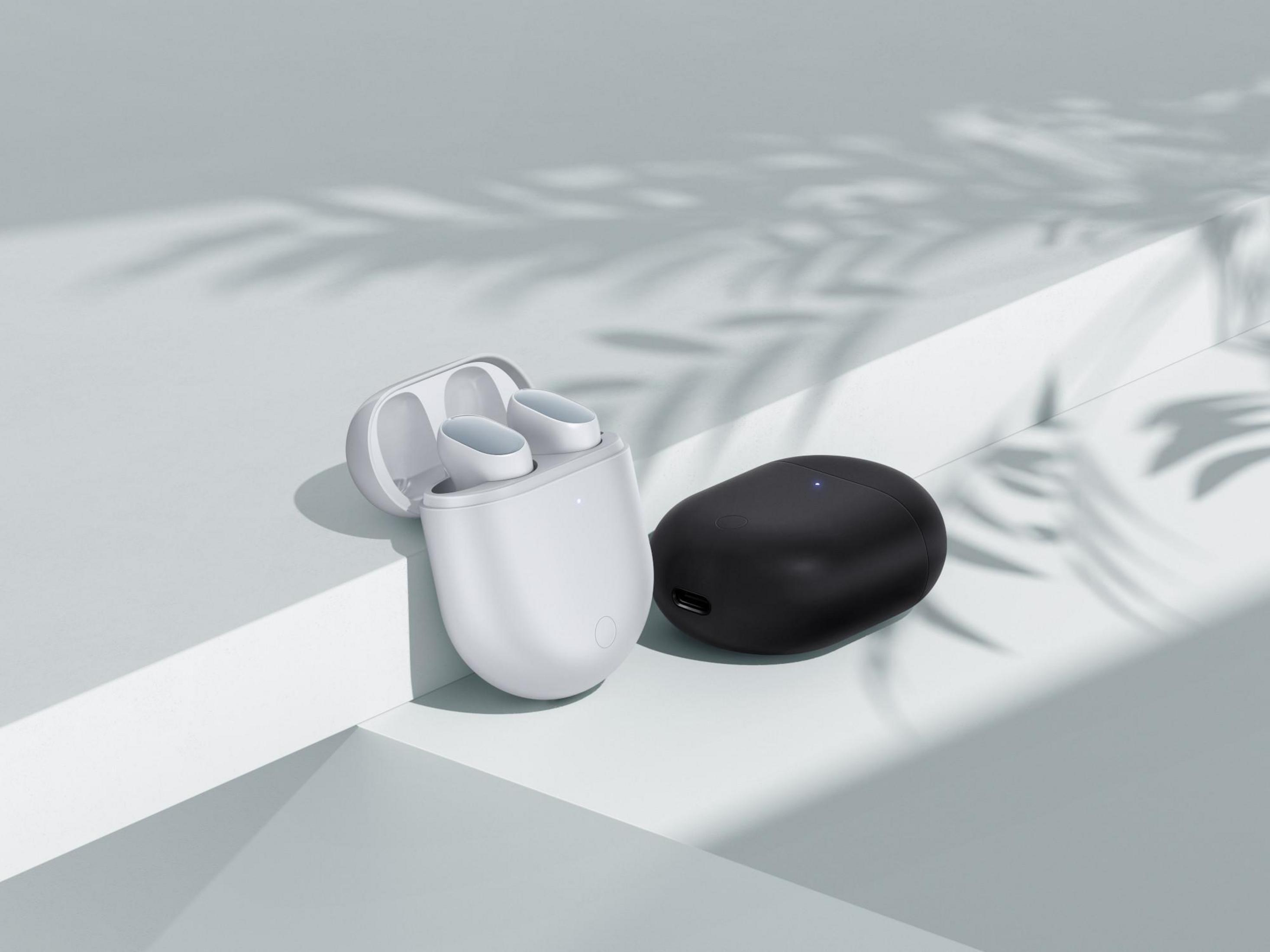 Auriculares inalámbricos blancos y negros con estuche de carga sobre superficie blanca.