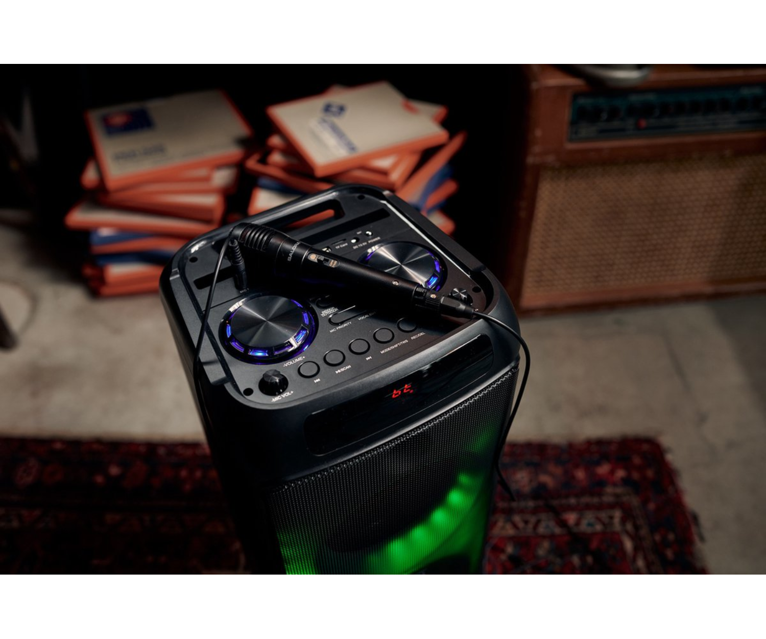 Enceinte de karaoké noire avec microphone sur un tapis. Fond sombre.