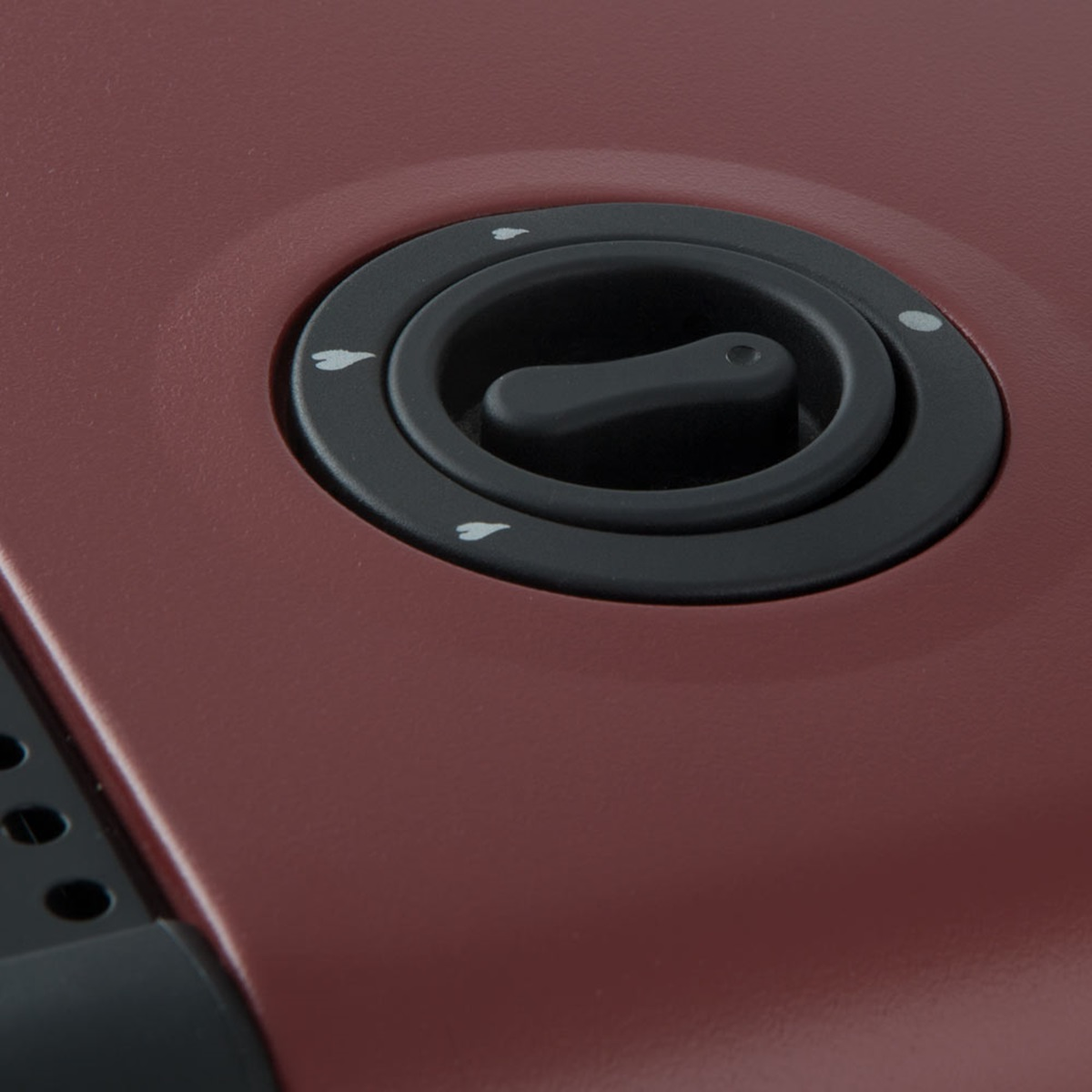 Primer plano de un panel de control rojo oscuro con un dial y flechas.