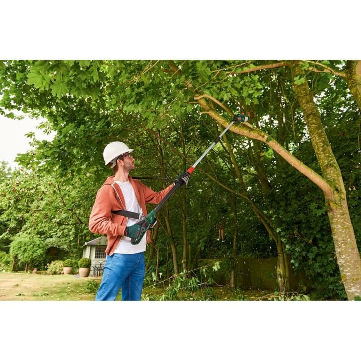 Ein Mann mit weißem Helm schneidet einen Ast mit einer Stangensäge in einem Wald.