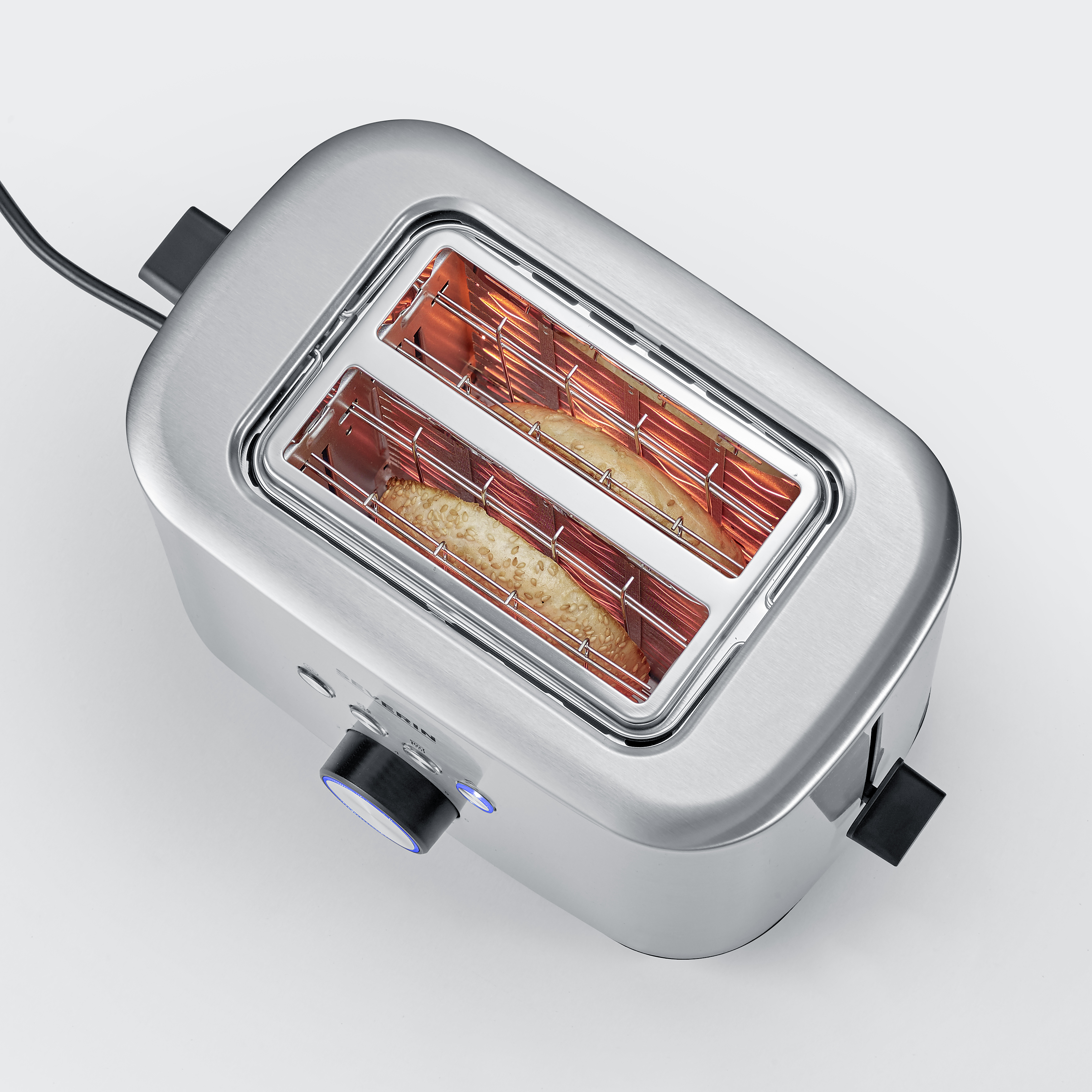Silver toaster with two slots. Two slices of bread are inside, with red heating elements visible.