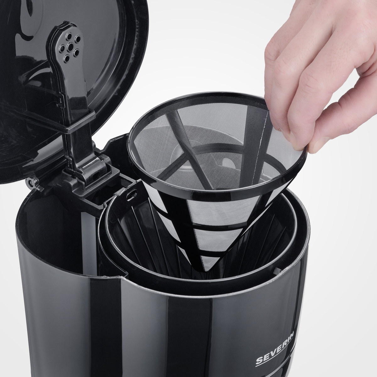 A hand holding a coffee filter on a black coffee machine.