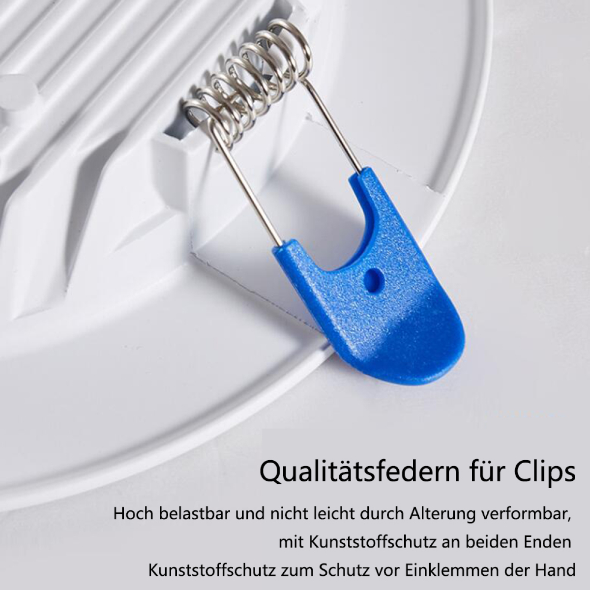 Weiße Platte mit Metallfederclip, blauem Kunststoffschutz und Text.