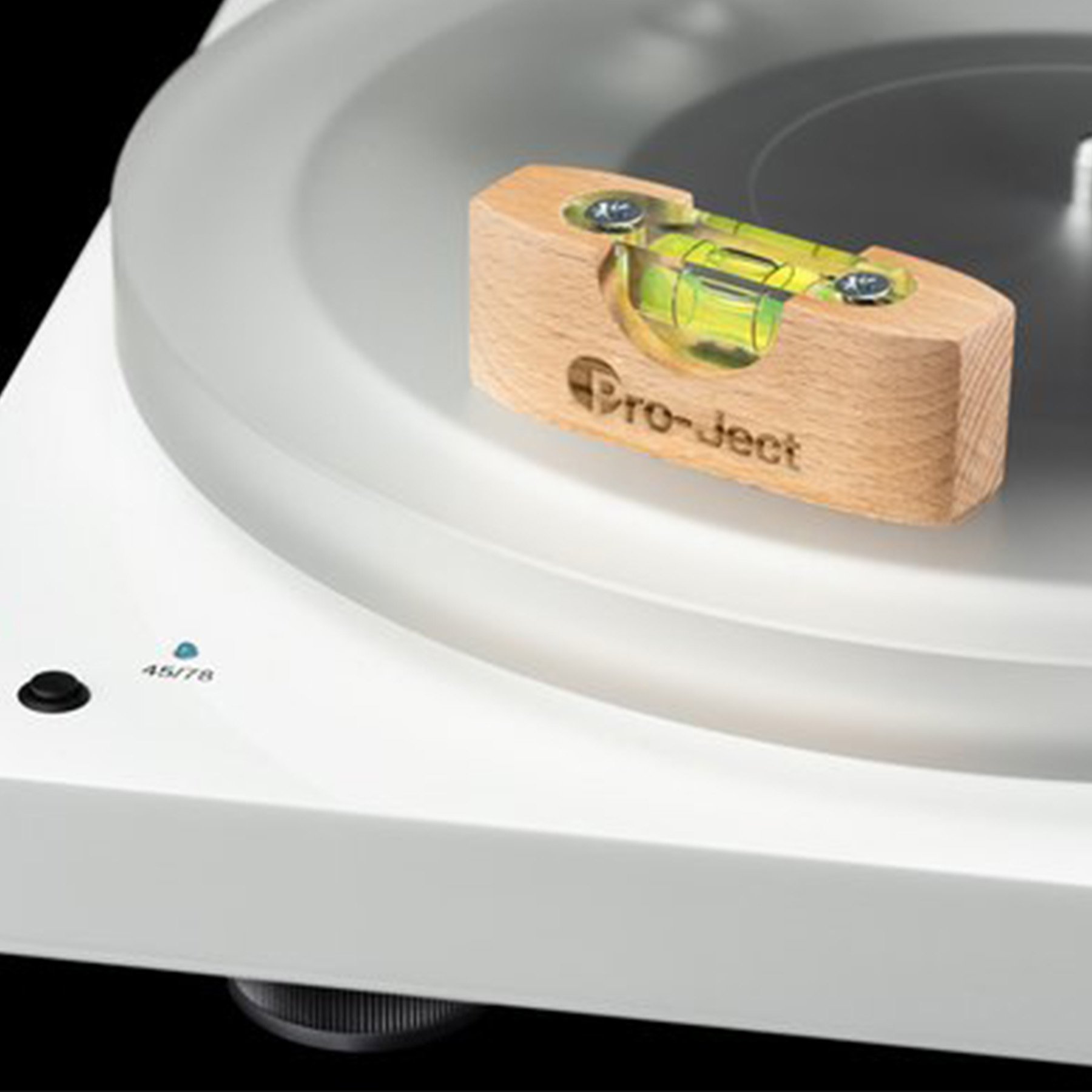 Gramofon z drewnianą poziomicą. Poziomica jest umieszczona na przezroczystym dysku gramofonu. Tekst: Pro-ject.