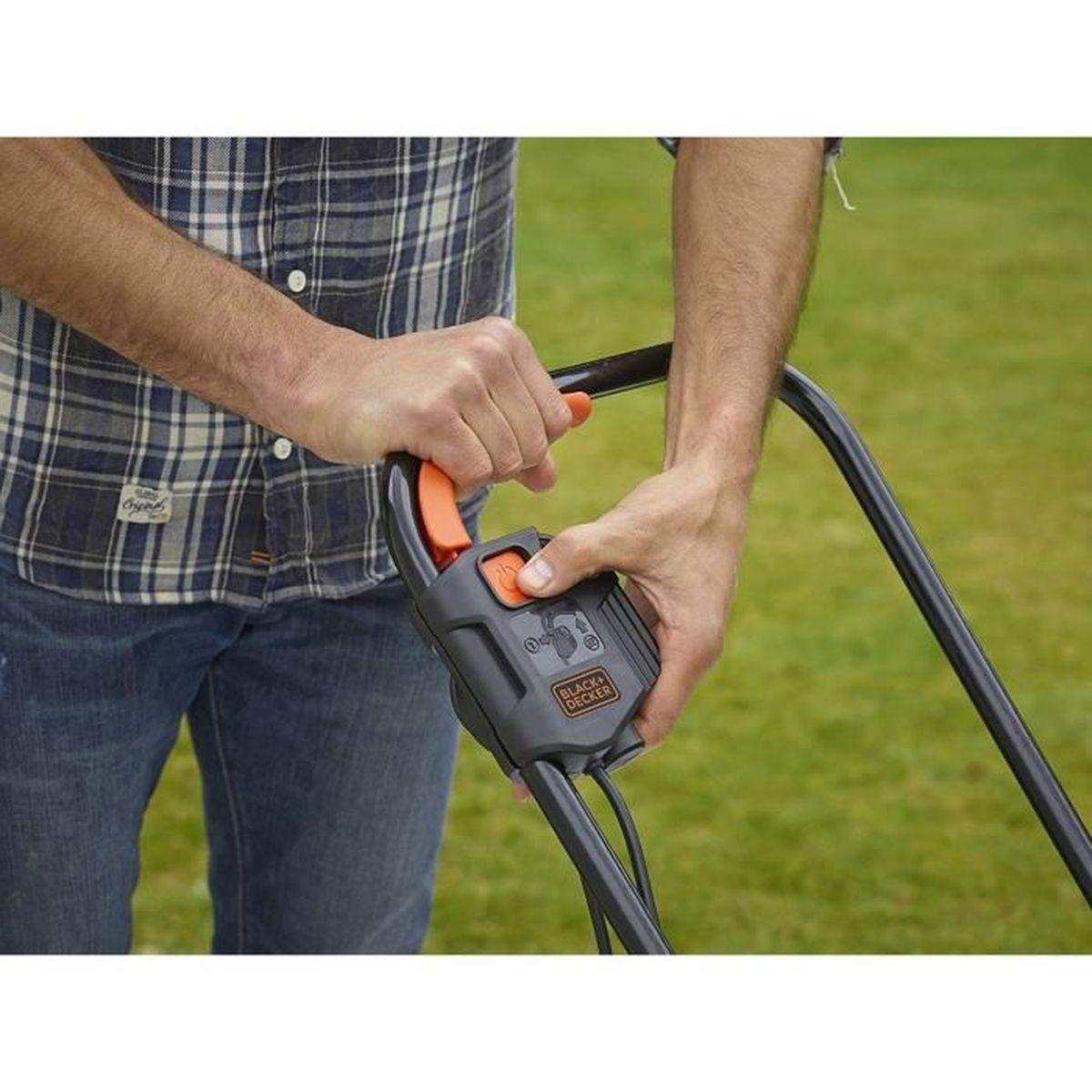 Ein Mann hält einen schwarz-orangenen Rasenmähergriff. Grüner Rasen im Hintergrund.
