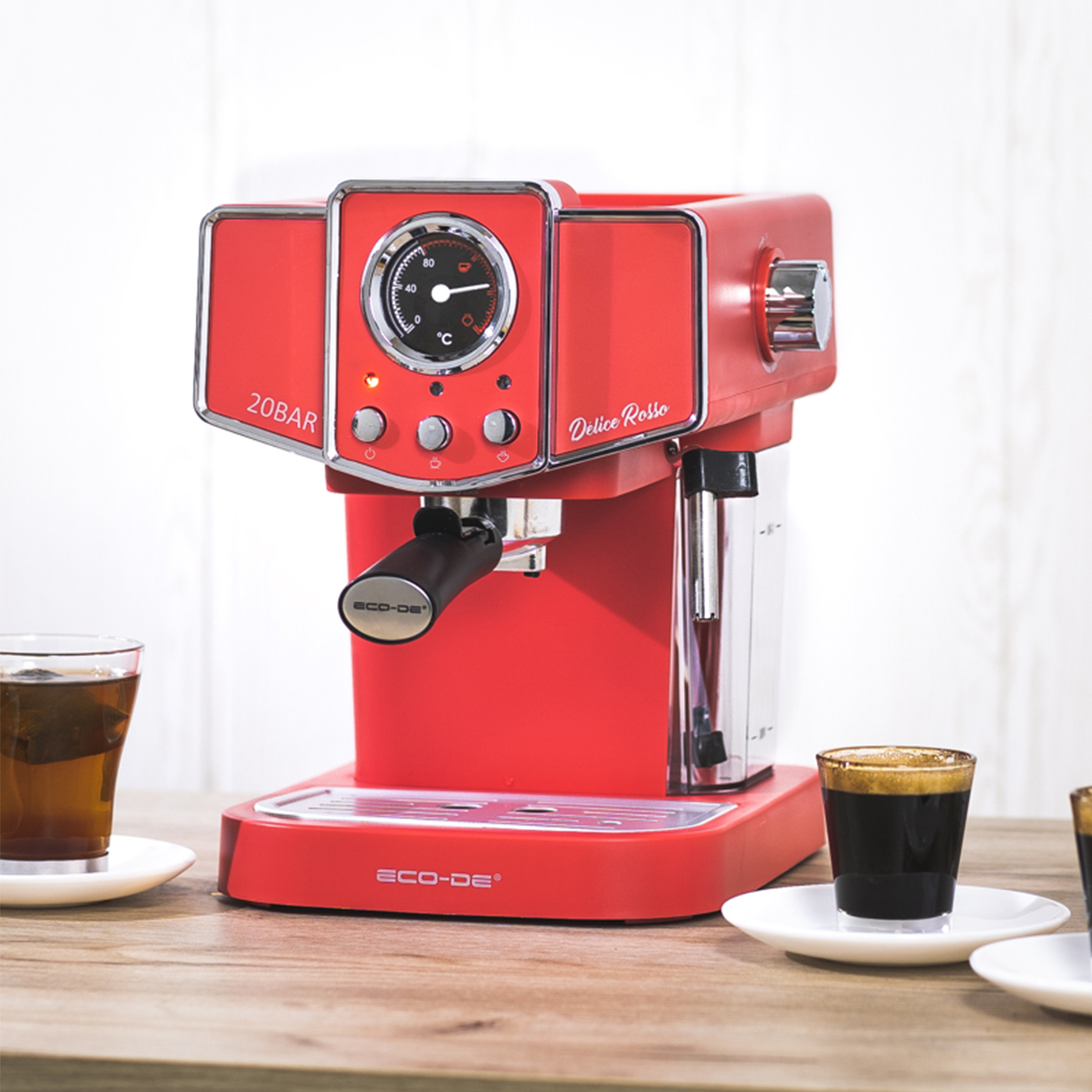 Máquina de espresso roja con medidor y dos tazas de café sobre una mesa de madera.