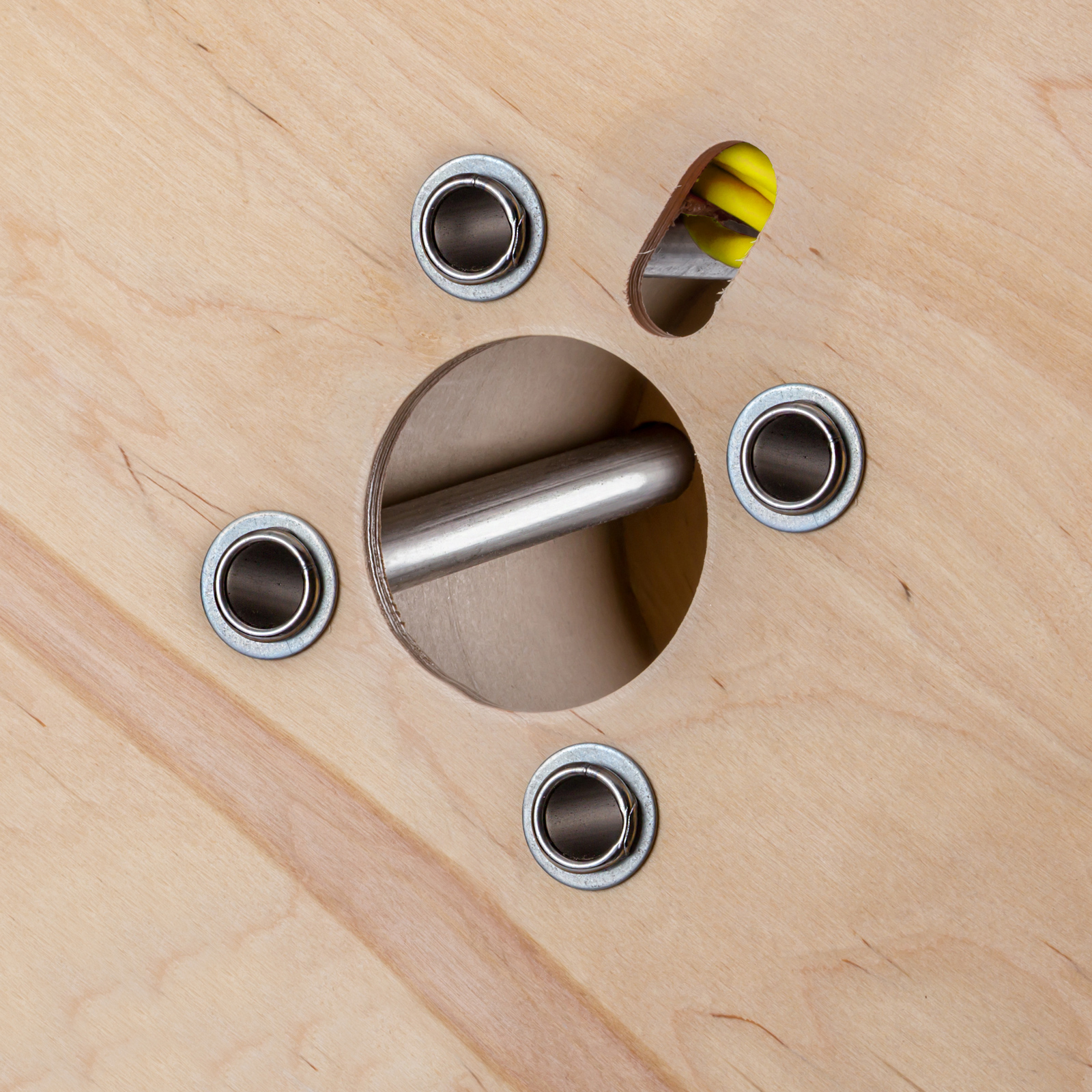 Holztisch mit silbernen Metallakzenten. Ein Loch hat eine Metallstange.