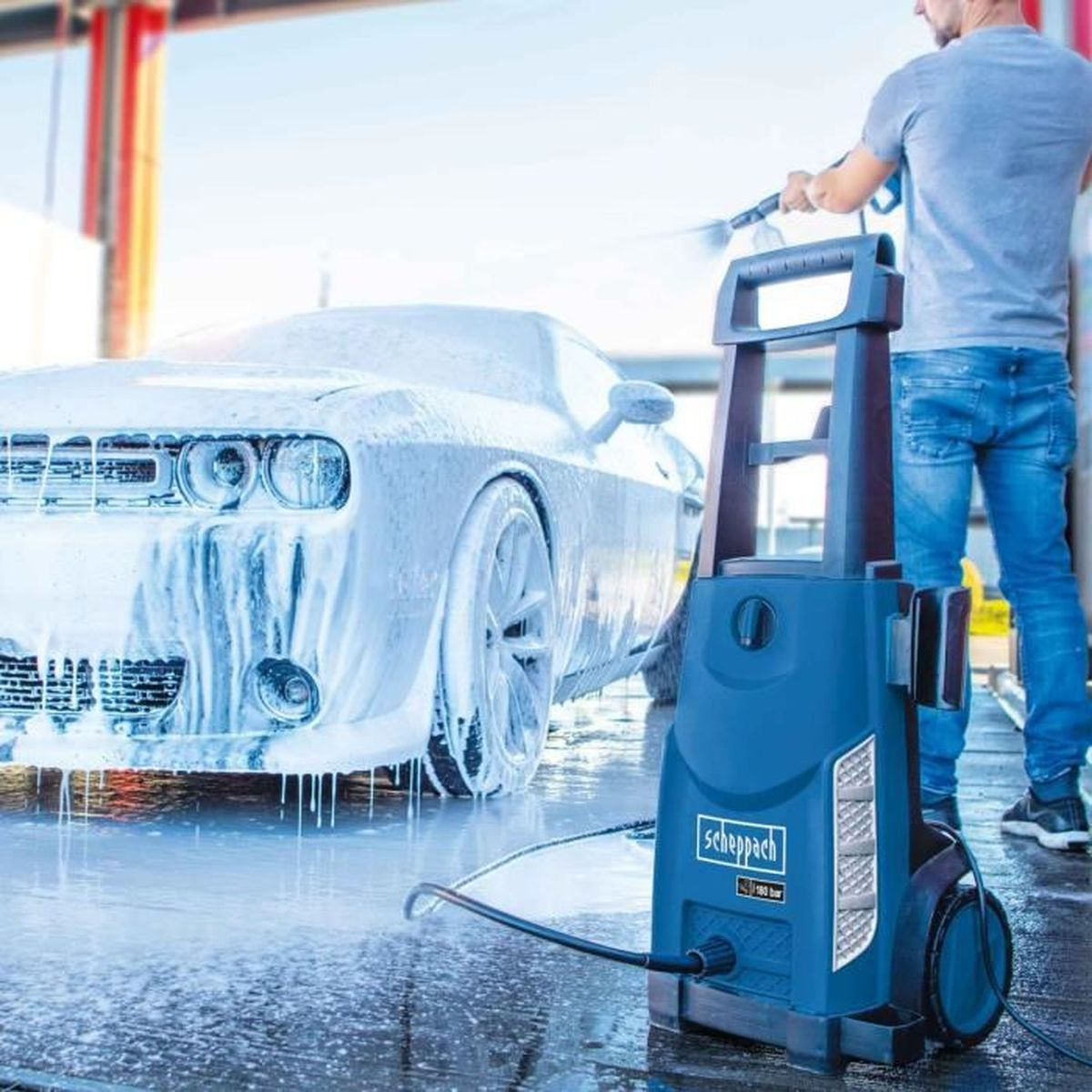 Eine Person wäscht ein Auto mit einem Hochdruckreiniger. Das Auto ist mit Schaum bedeckt, und der Reiniger ist blau.