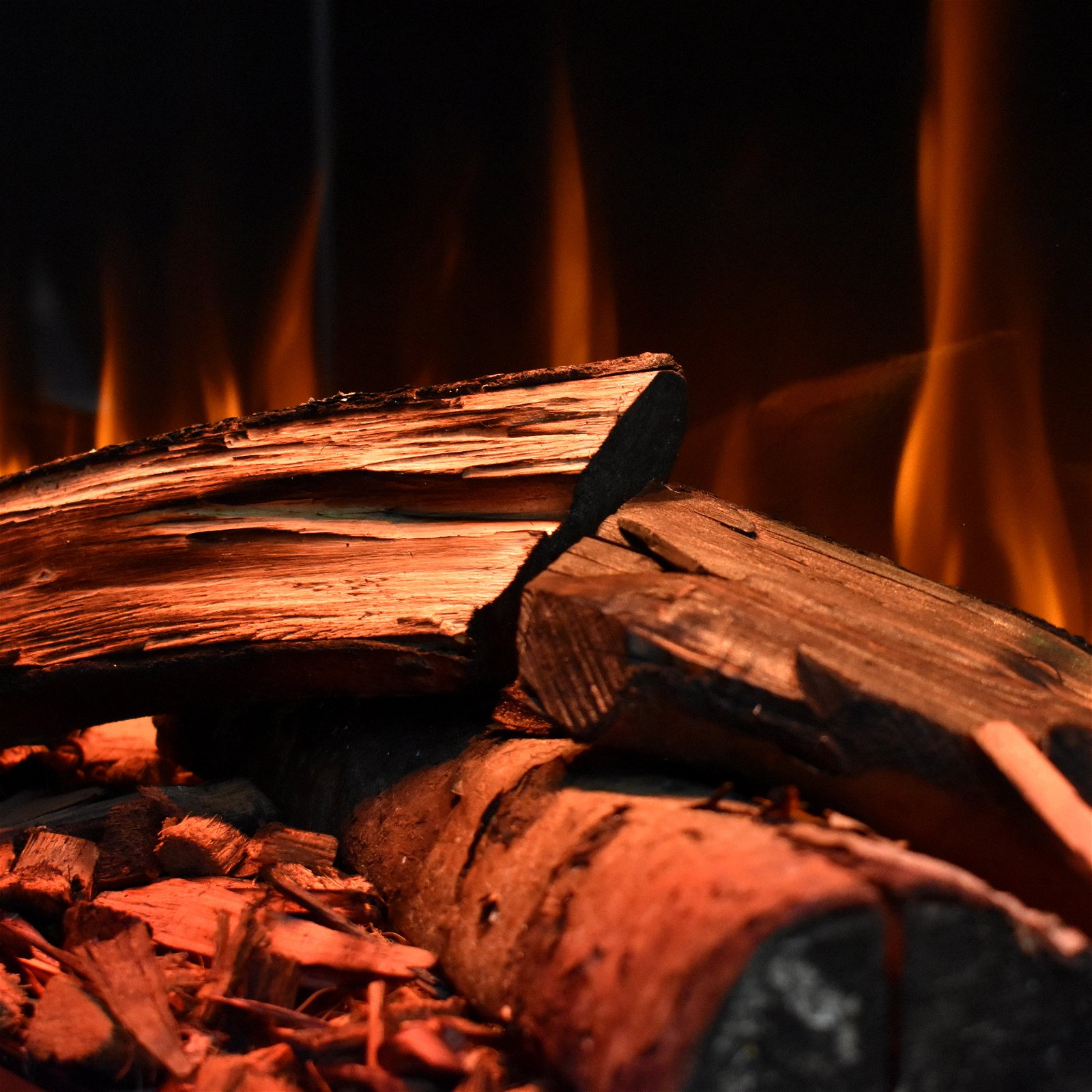 Nahaufnahme von brennendem Holz. Flammen sind orangefarben vor schwarzem Hintergrund. Das Holz ist braun.