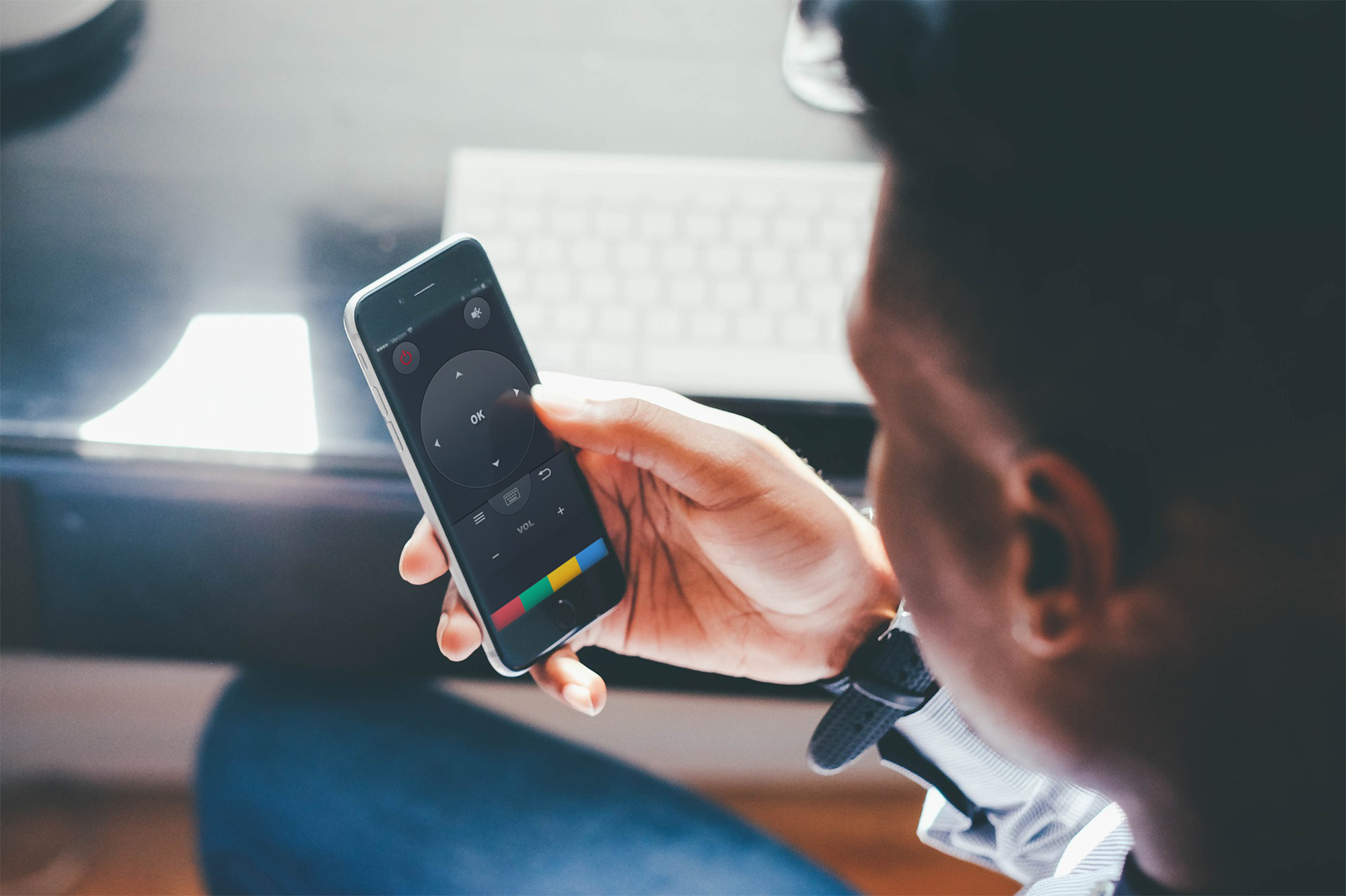 Die Hand einer Person, die ein Smartphone mit Touchscreen-Bedienelementen hält. Weiße Tastatur im Hintergrund.