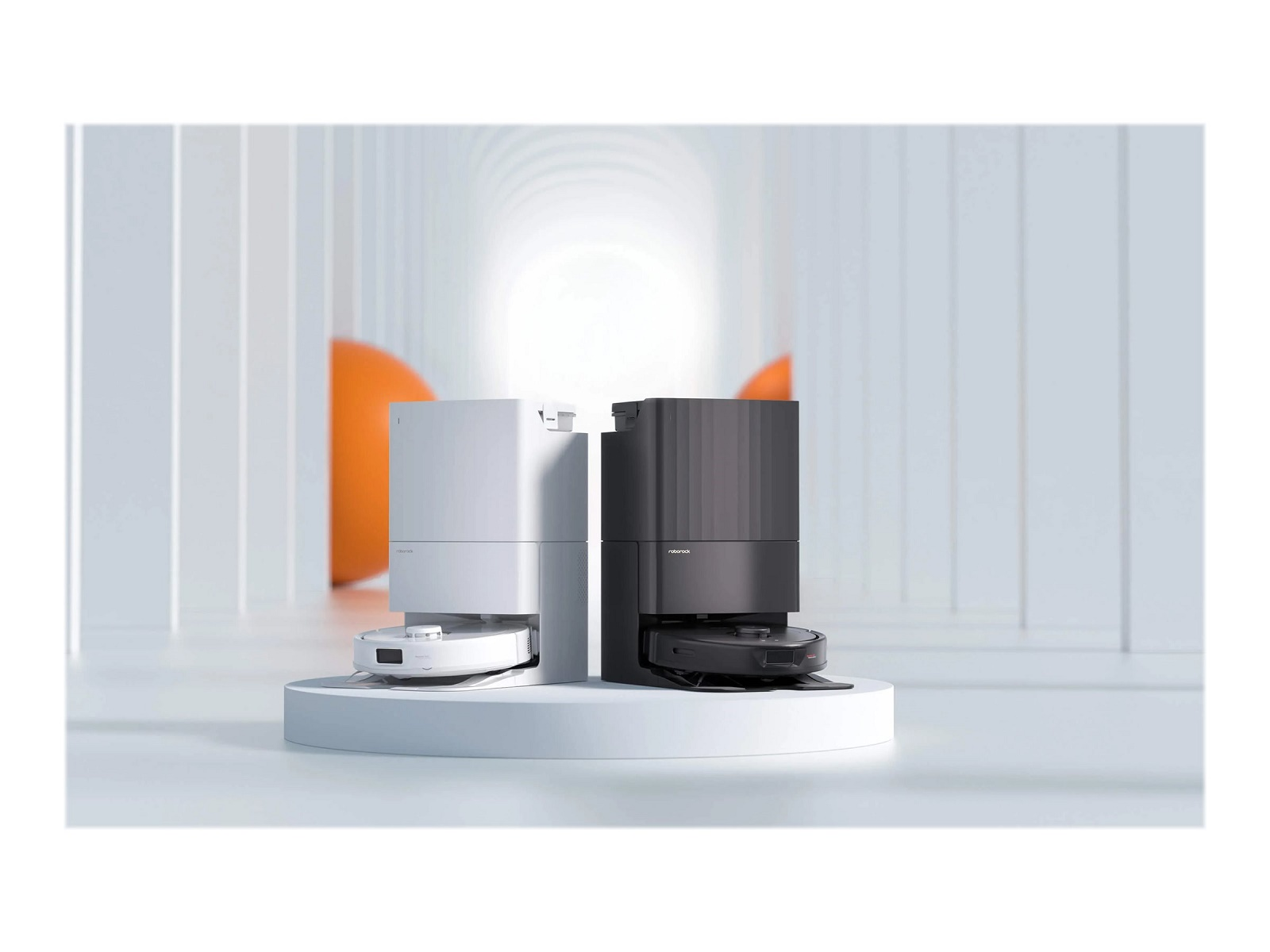 Zwei Roboter-Staubsauger, schwarz und weiß, stehen auf einer Plattform, mit weißem und orangem Hintergrund.