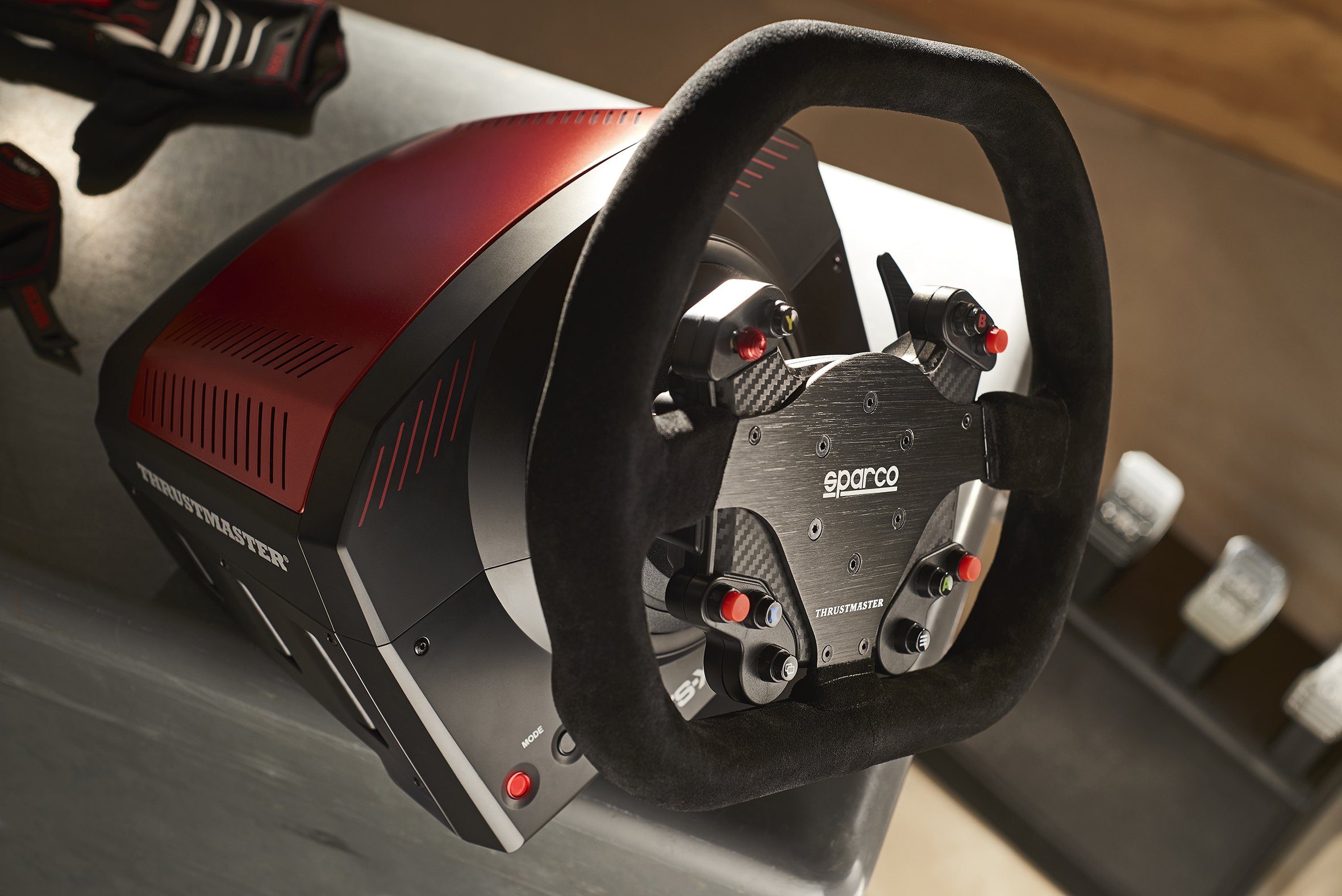 Un volante de carreras Thrustmaster Sparco con detalles rojos y borde negro de ante.
