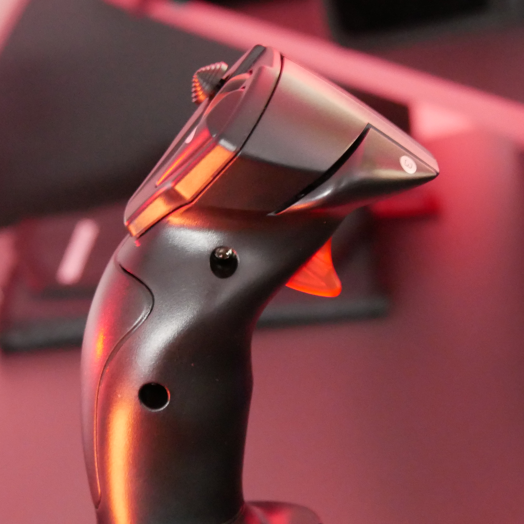 Zbliżenie czarnego joysticka. Czerwony spust. Joystick jest ustawiony pod kątem.