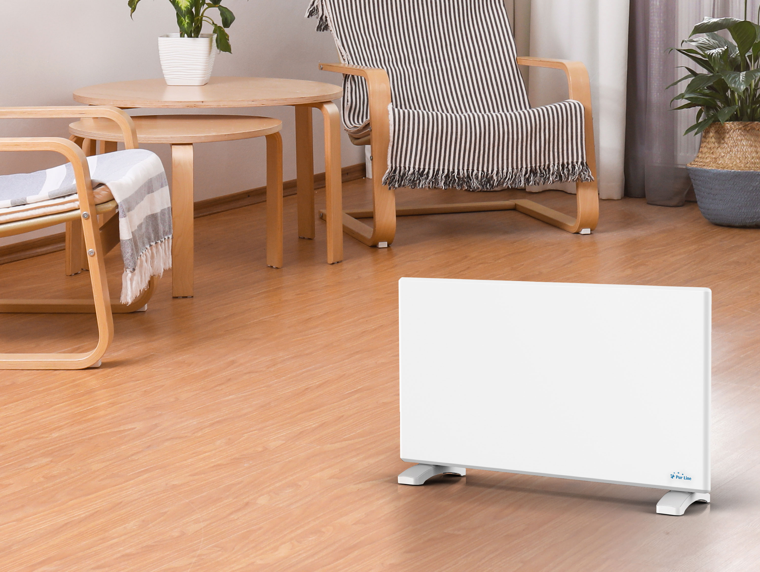 Eine weiße Elektroheizung auf einem Holzboden in einem Wohnzimmer mit Möbeln.