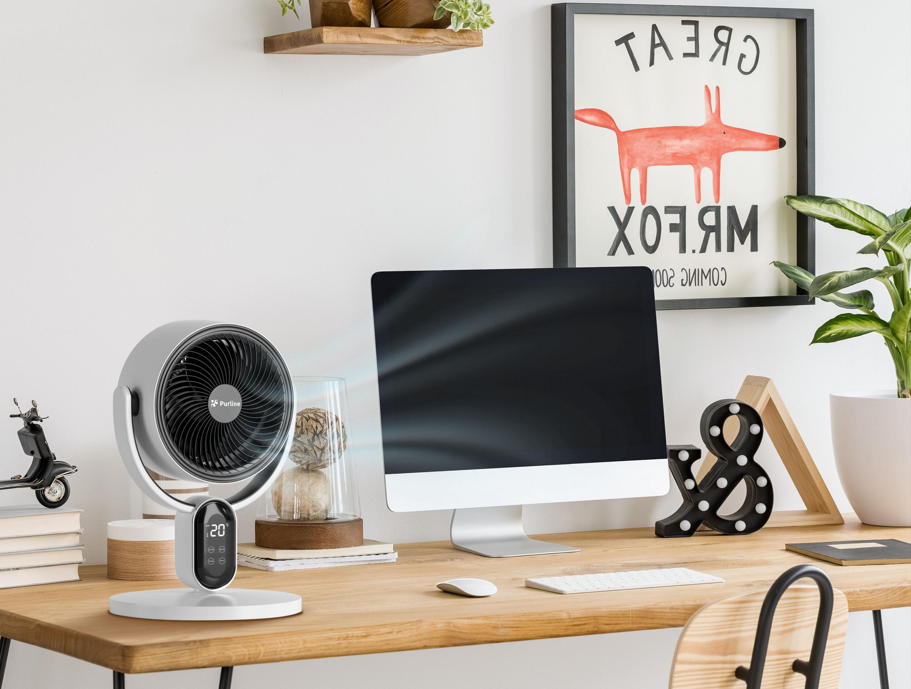 Escritorio con ventilador, monitor, decoración y obras de arte. Contiene un juguete de scooter y una planta.
