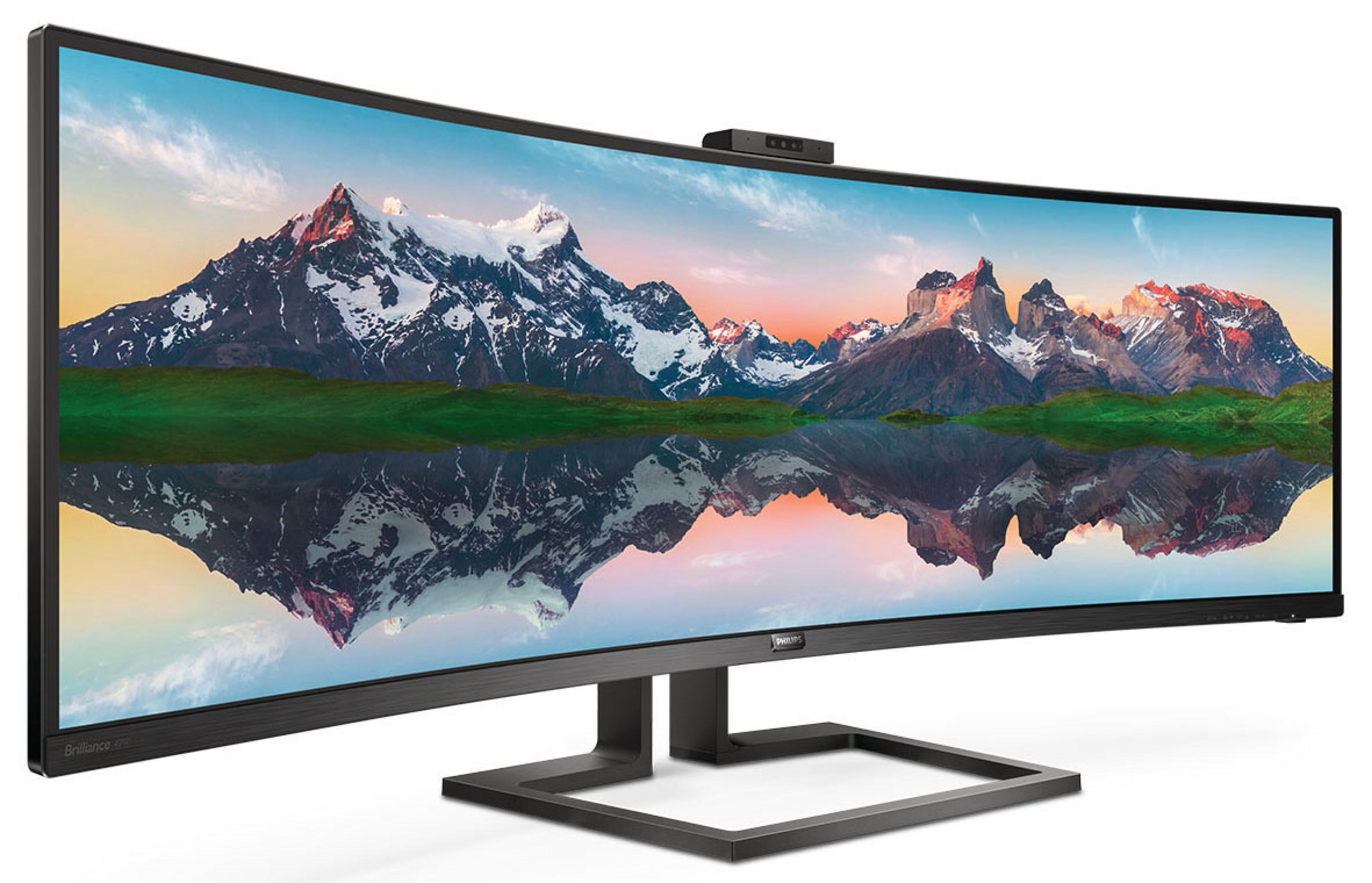 Zakrzywiony monitor wyświetlający górski krajobraz. Kamera internetowa na górze. Czarny stojak.