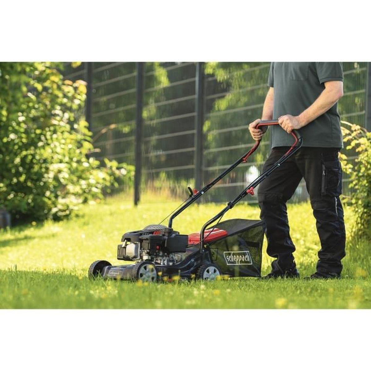 Een persoon die gras maait met een zwart-rode grasmaaier in een tuin.
