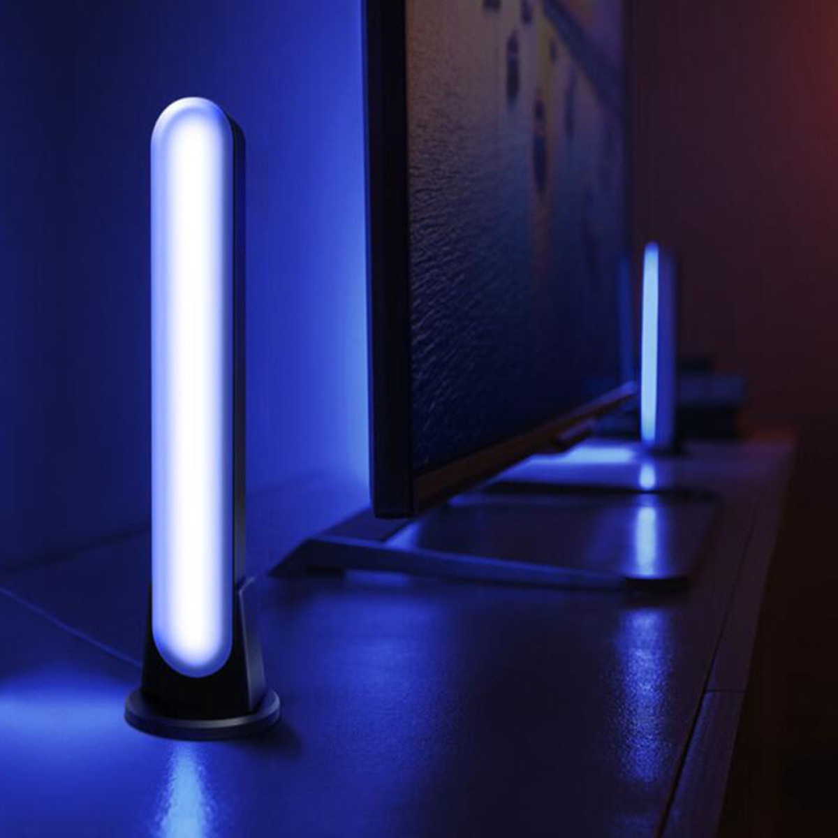 Blaue Lichtleiste auf einem Tisch. Im Hintergrund ein Fernseher und eine weitere Lichtleiste.