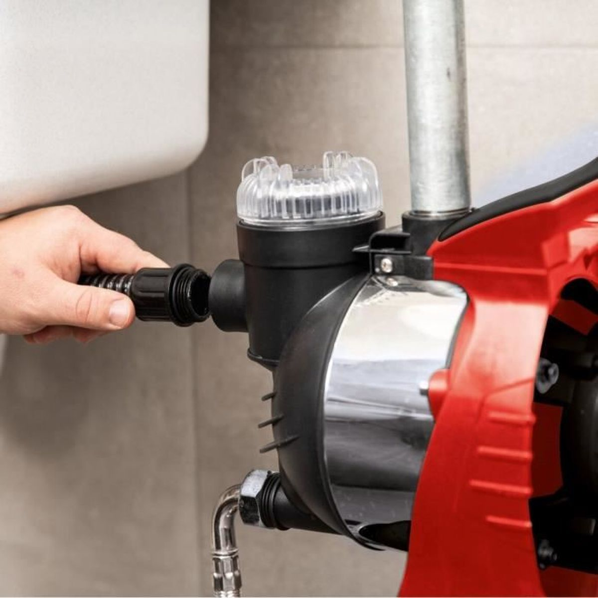 Hand verbindet schwarzen Schlauch mit einem rot-schwarzen Wasserpumpensystem.