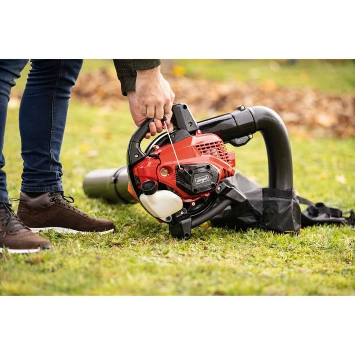 Osoba używająca czerwonej dmuchawy do liści Scheppach na trawniku.