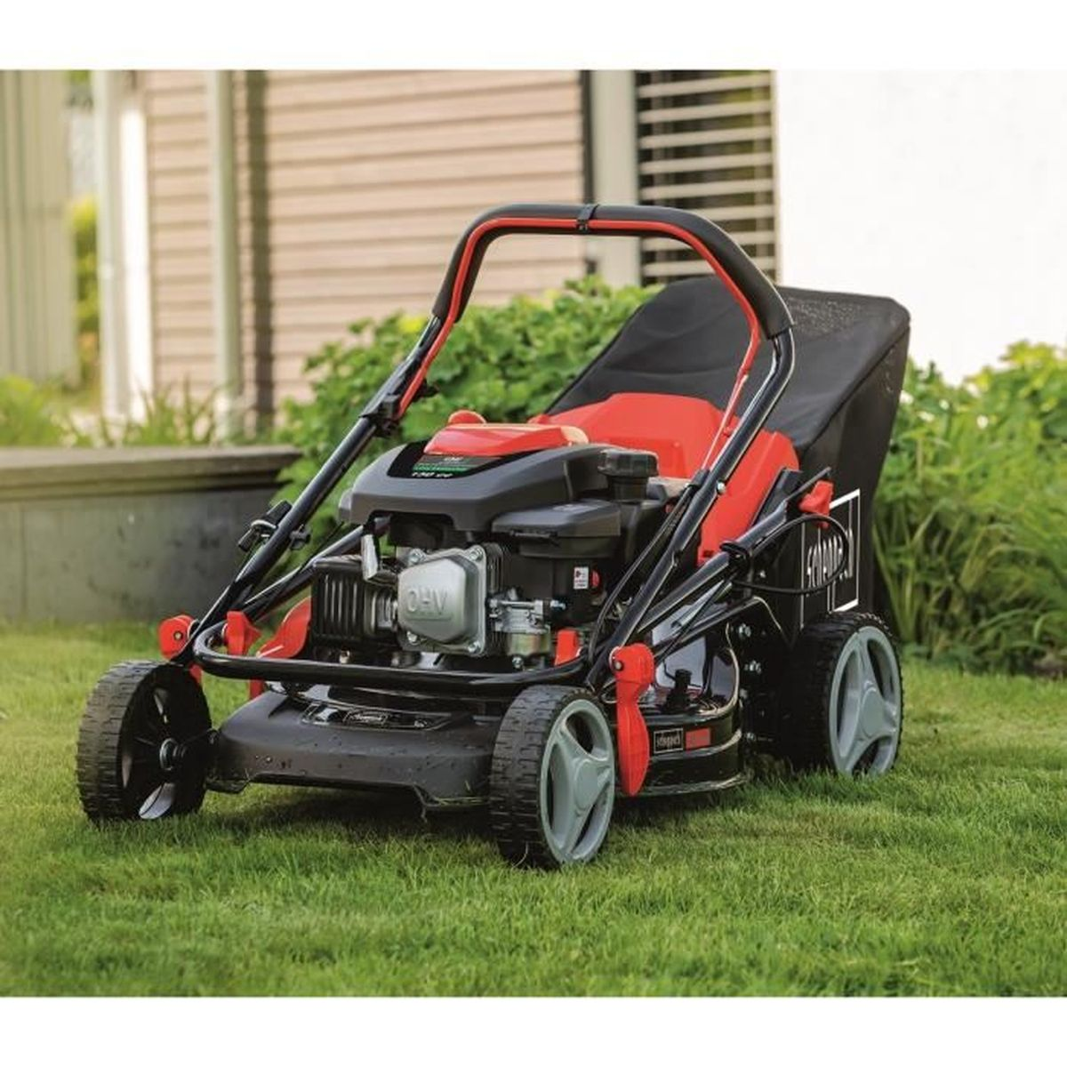 Rode en zwarte grasmaaier op gras met rode motor en zwarte zak.