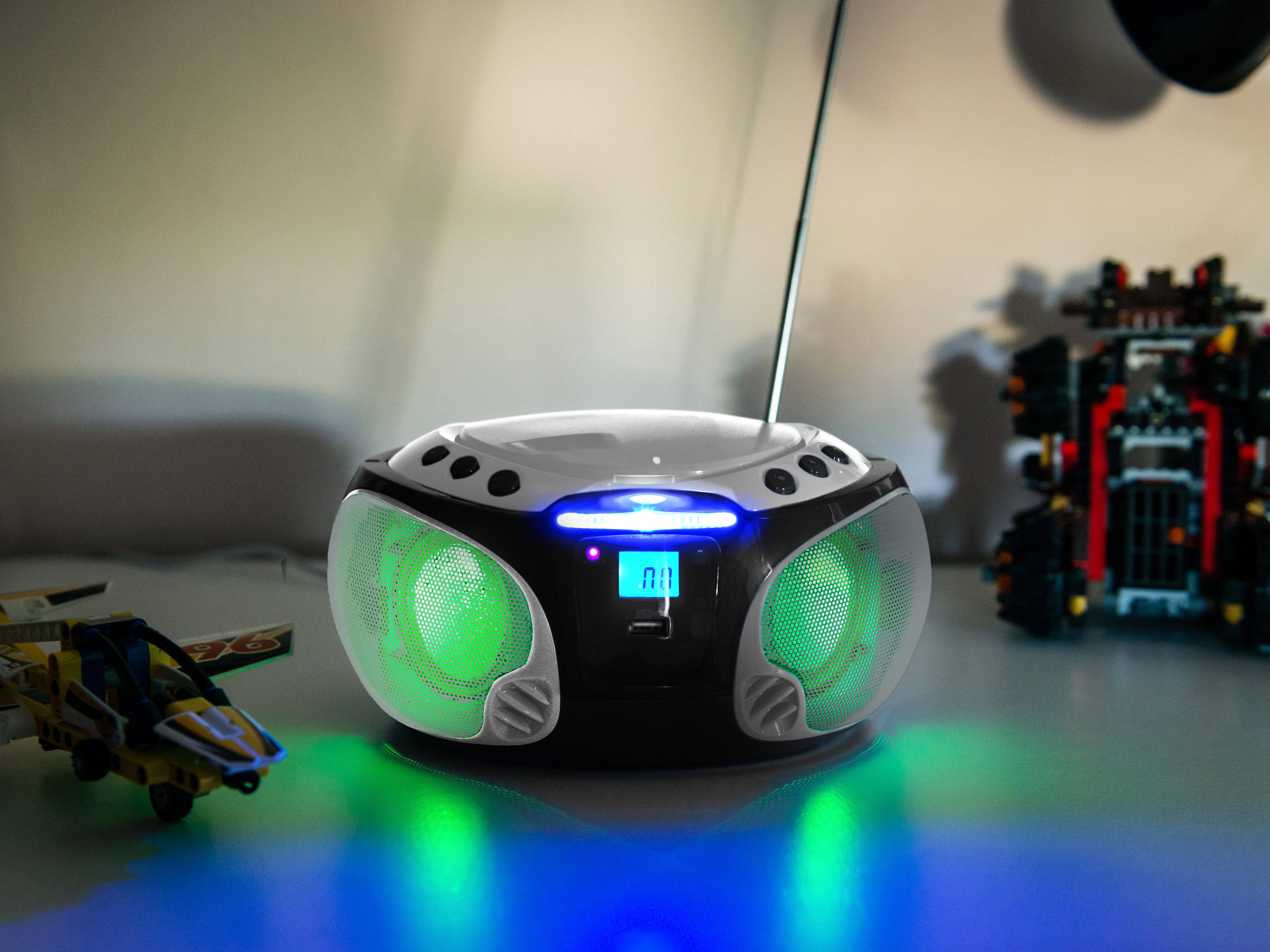Retro radio with green and blue lights, displaying a screen, and toy cars beside it.