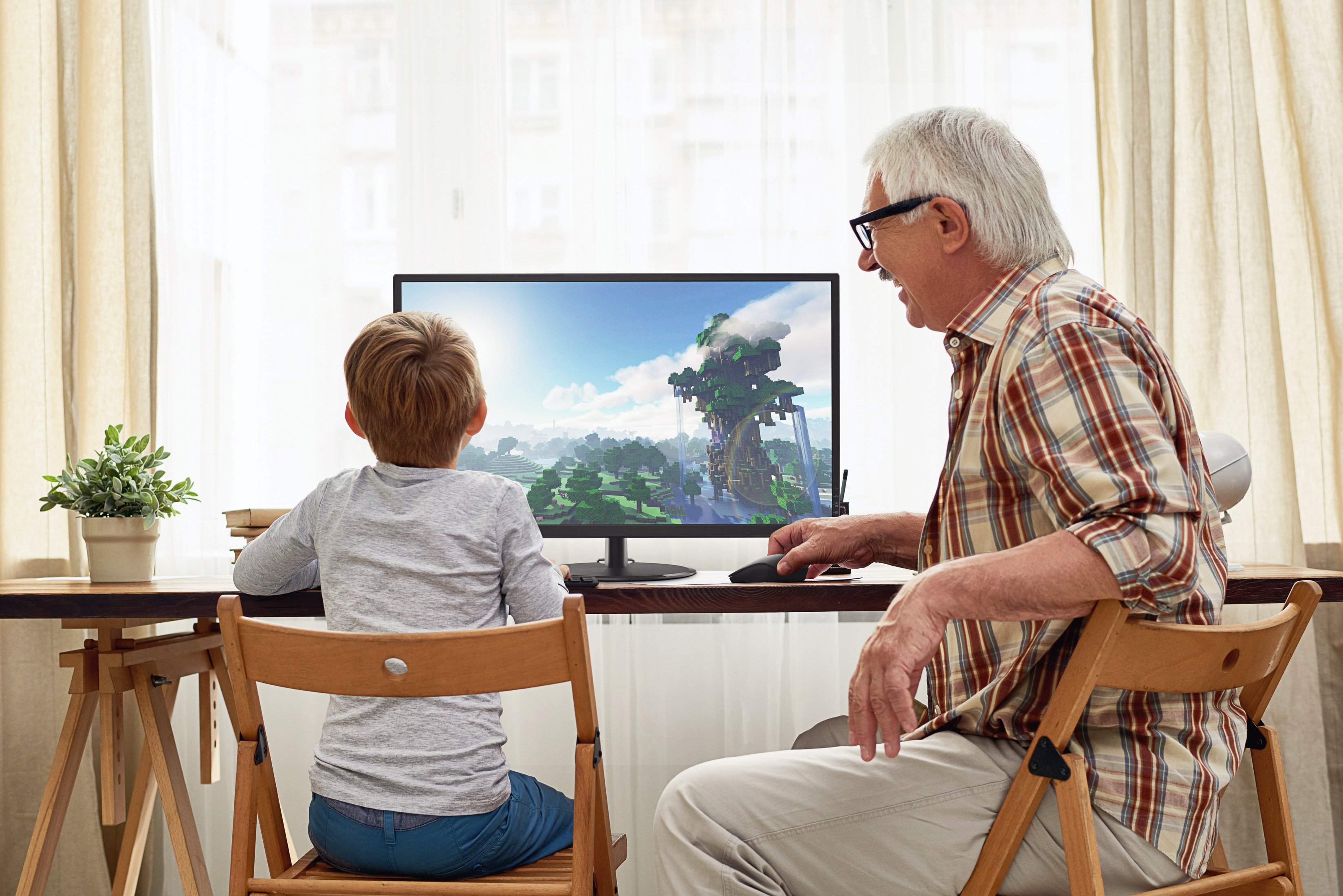 Chłopiec i mężczyzna razem patrzą na ekran komputera.