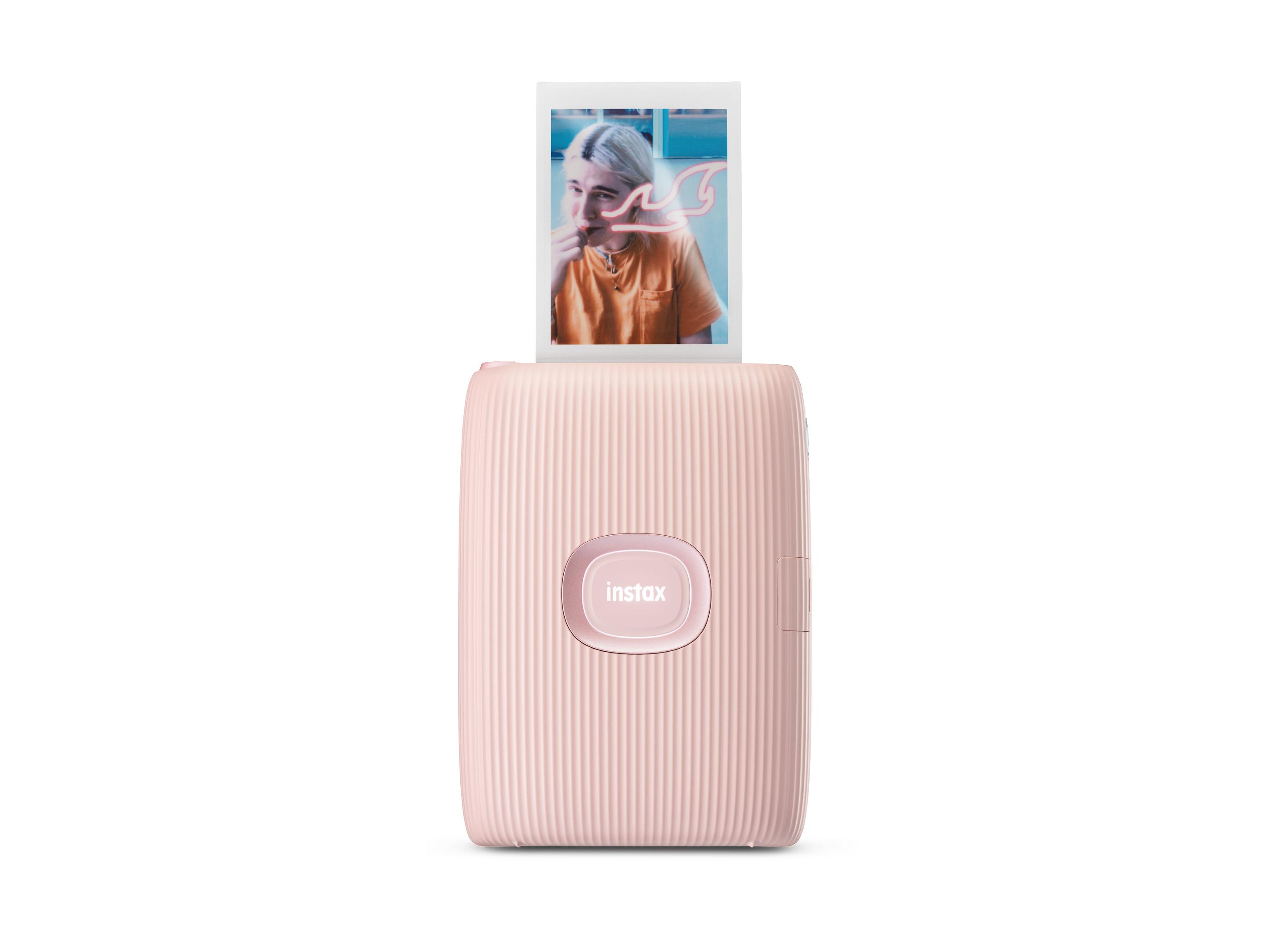 Różowa drukarka Instax Mini Link 2 drukująca zdjęcie osoby.
