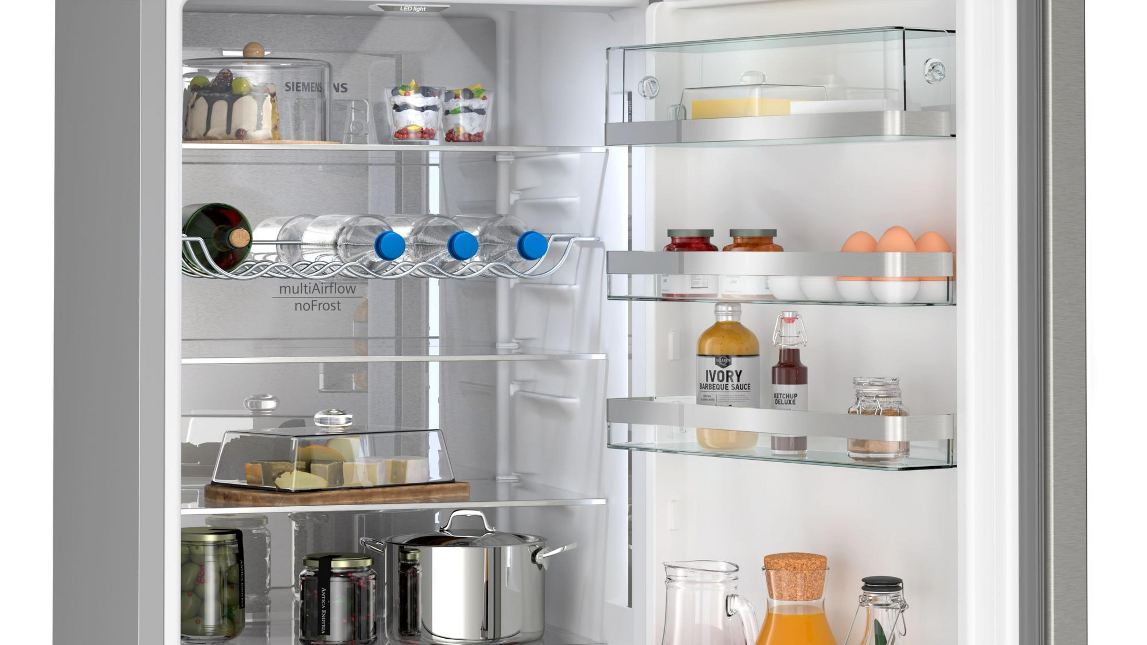 Offener Kühlschrank, gefüllt mit Lebensmitteln wie Kuchen, Getränken, Gläsern und Eiern.