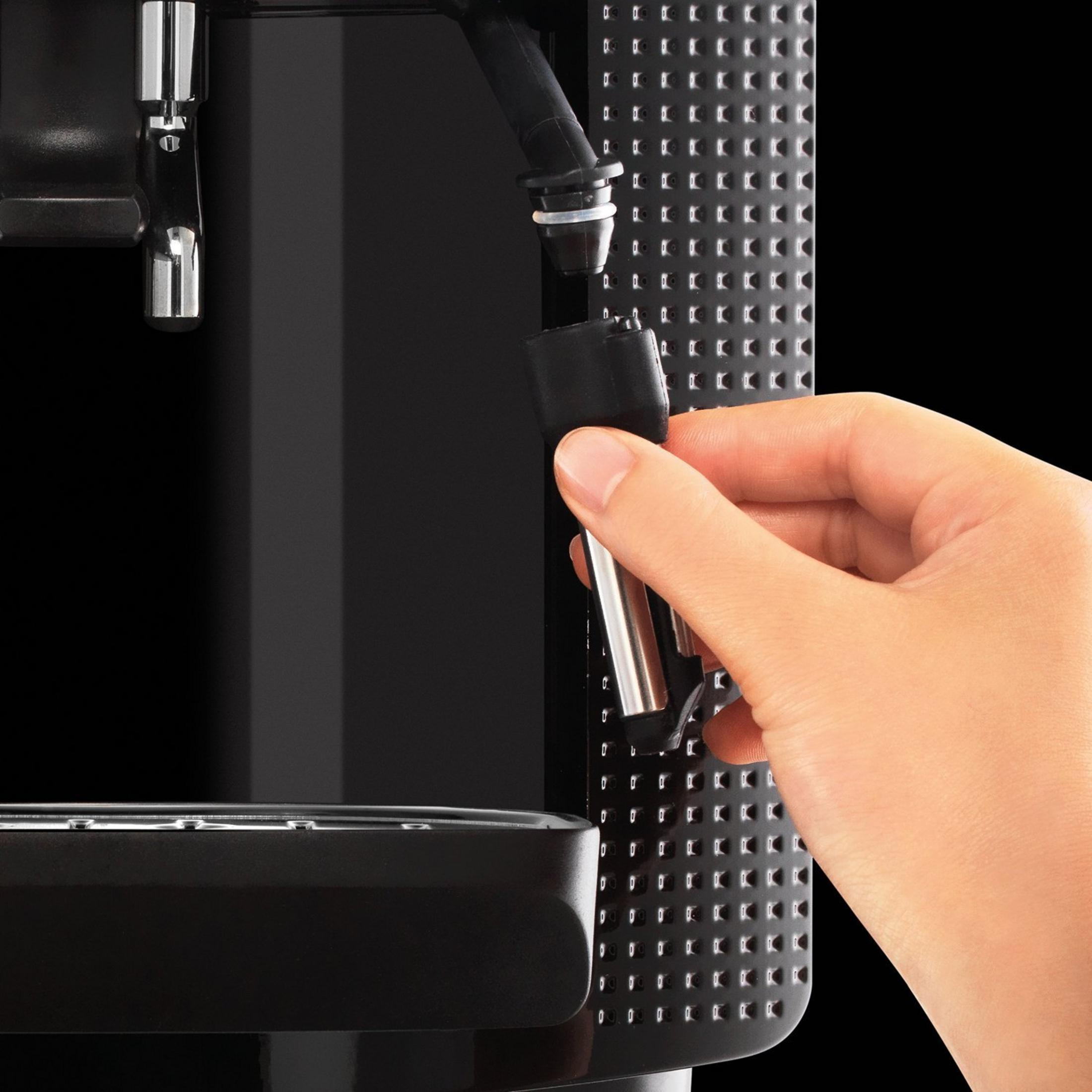 Hand, die eine Düse von einer schwarzen Kaffeemaschine hält.