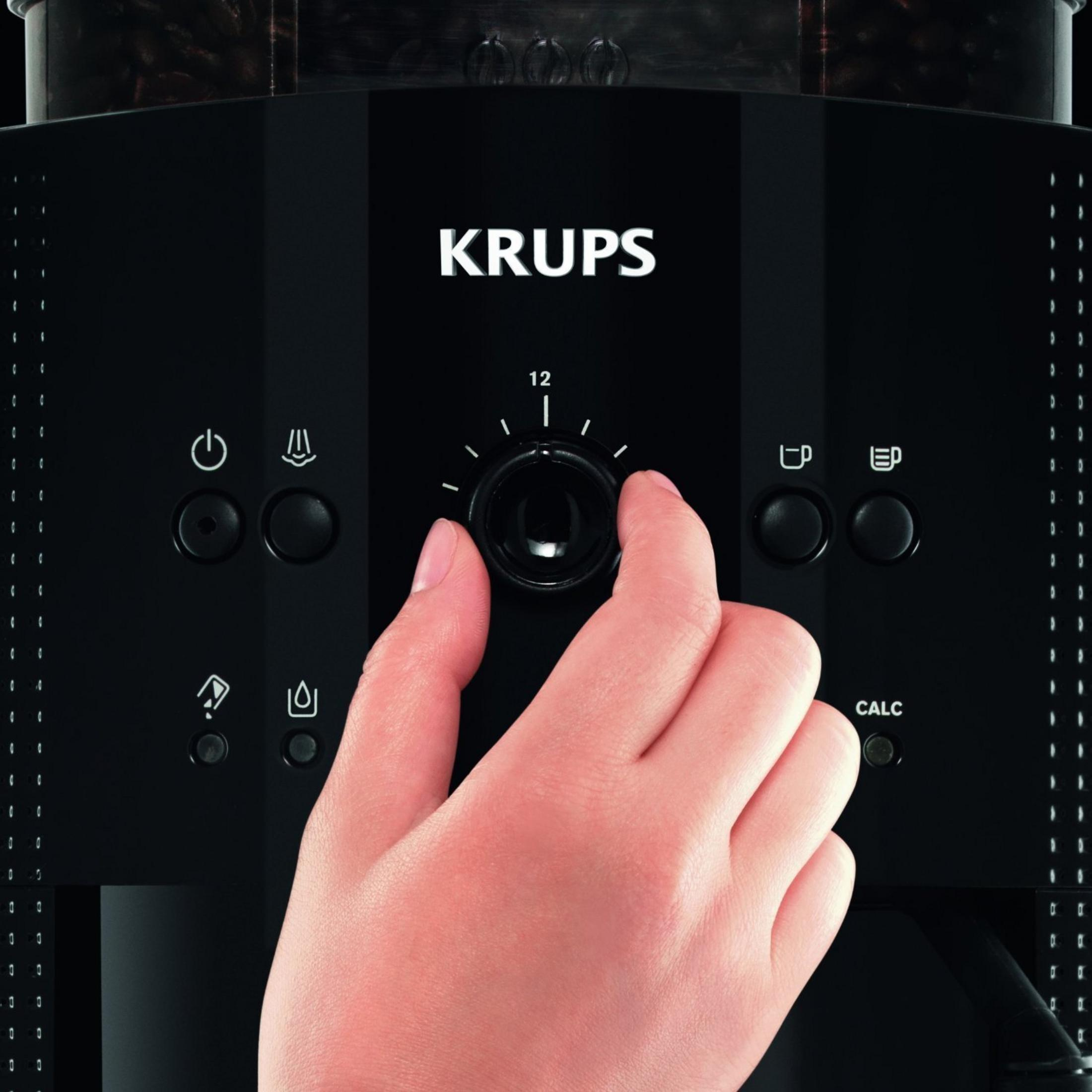 Eine Hand dreht einen Drehregler an einer schwarzen Krups Kaffeemaschine, Nahaufnahme.