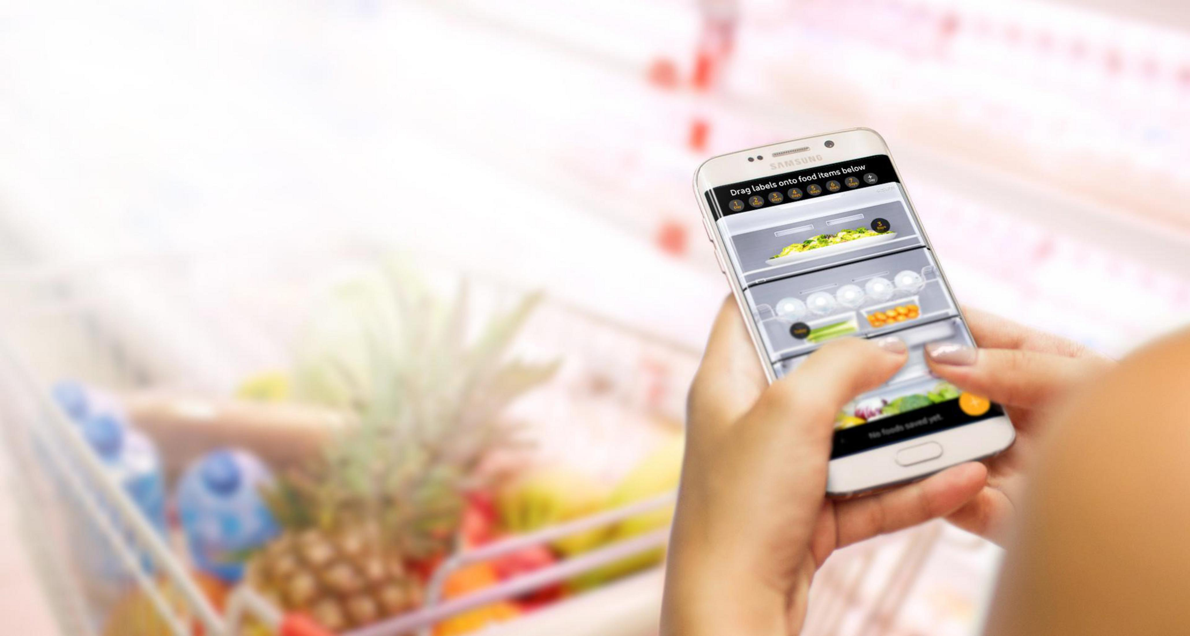 Osoba trzymająca smartfon z cyfrowym widokiem lodówki, widoczne etykiety.