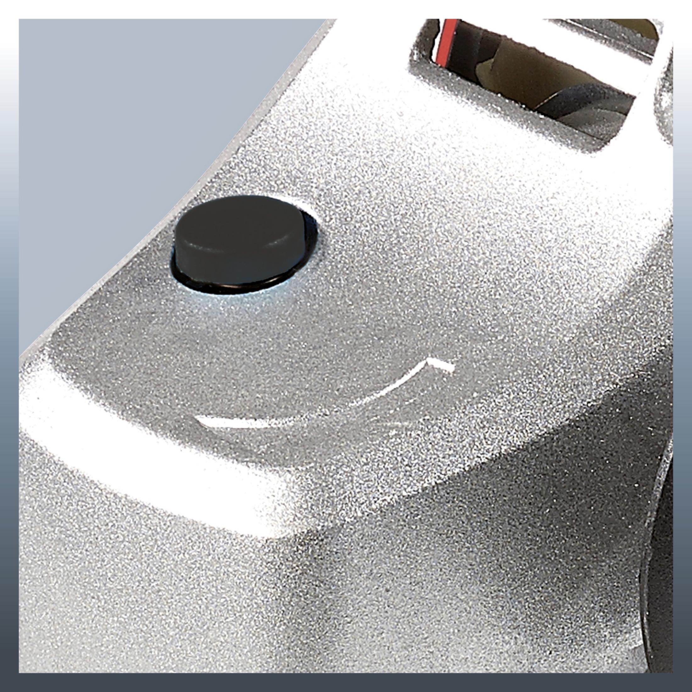 Zbliżenie srebrnej części maszyny z czarnym przyciskiem.