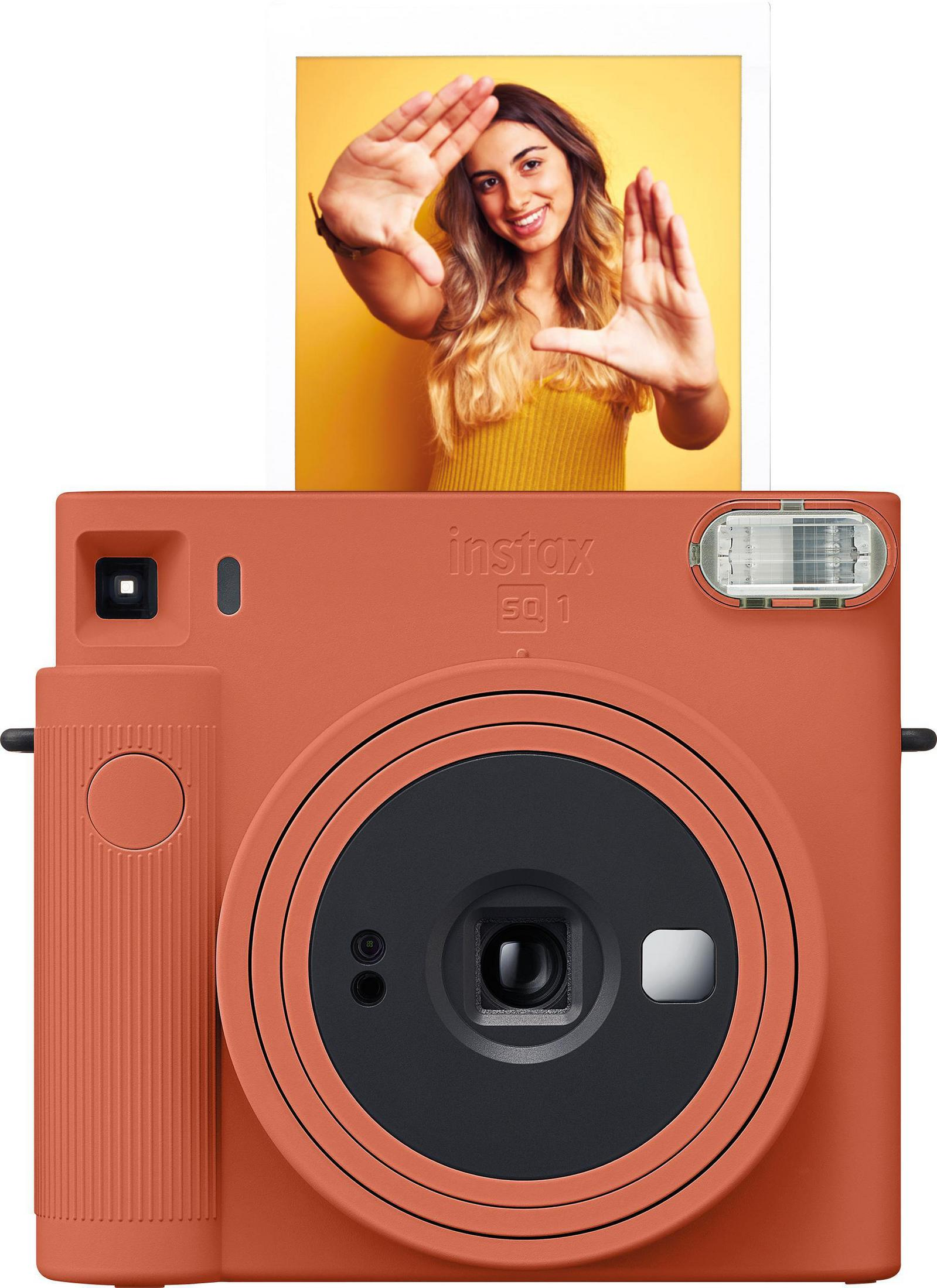 Eine orangefarbene Instax-Kamera mit einer Frau, die ein Foto hält.