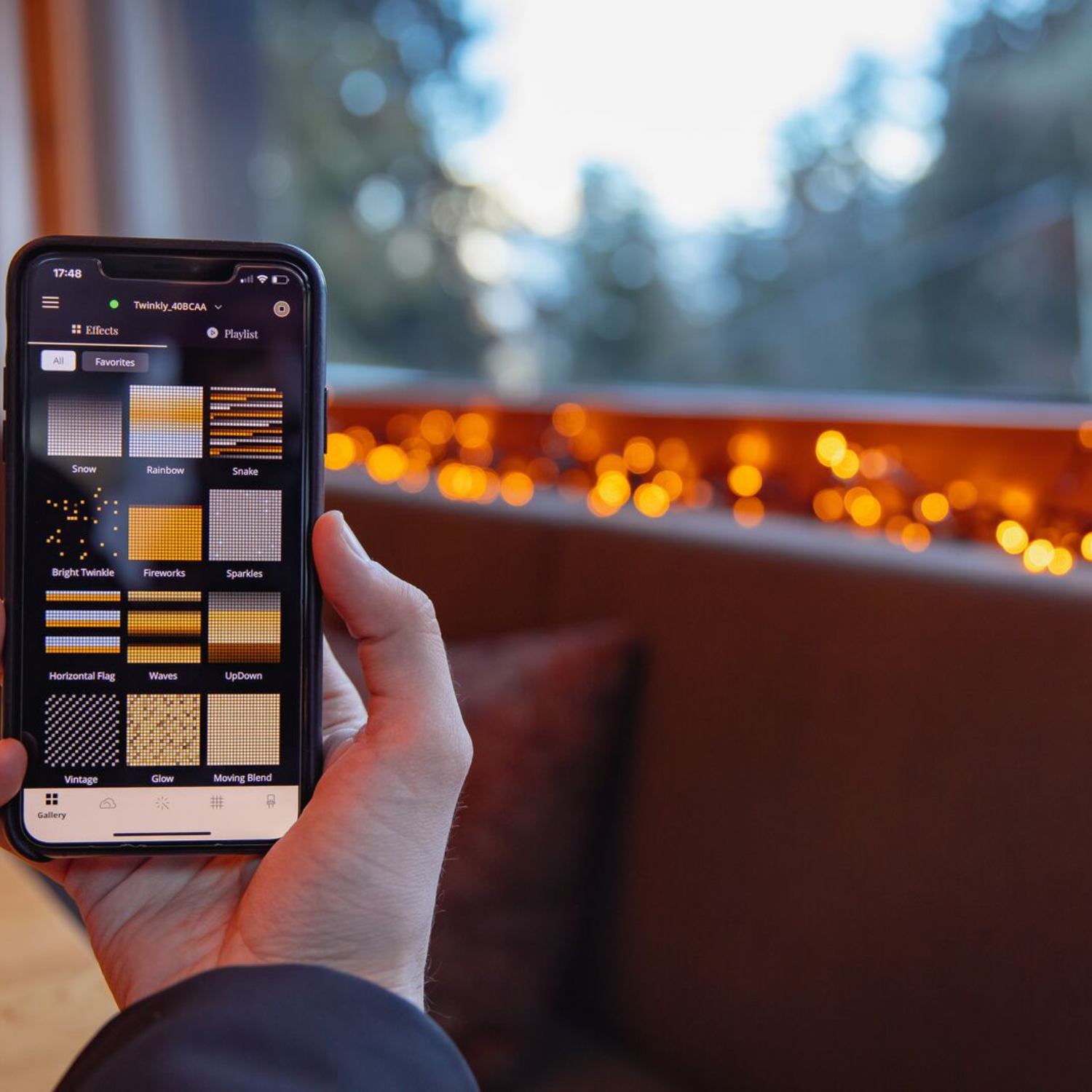 Osoba trzymająca telefon wyświetlający aplikację oświetleniową z różnymi efektami świetlnymi.