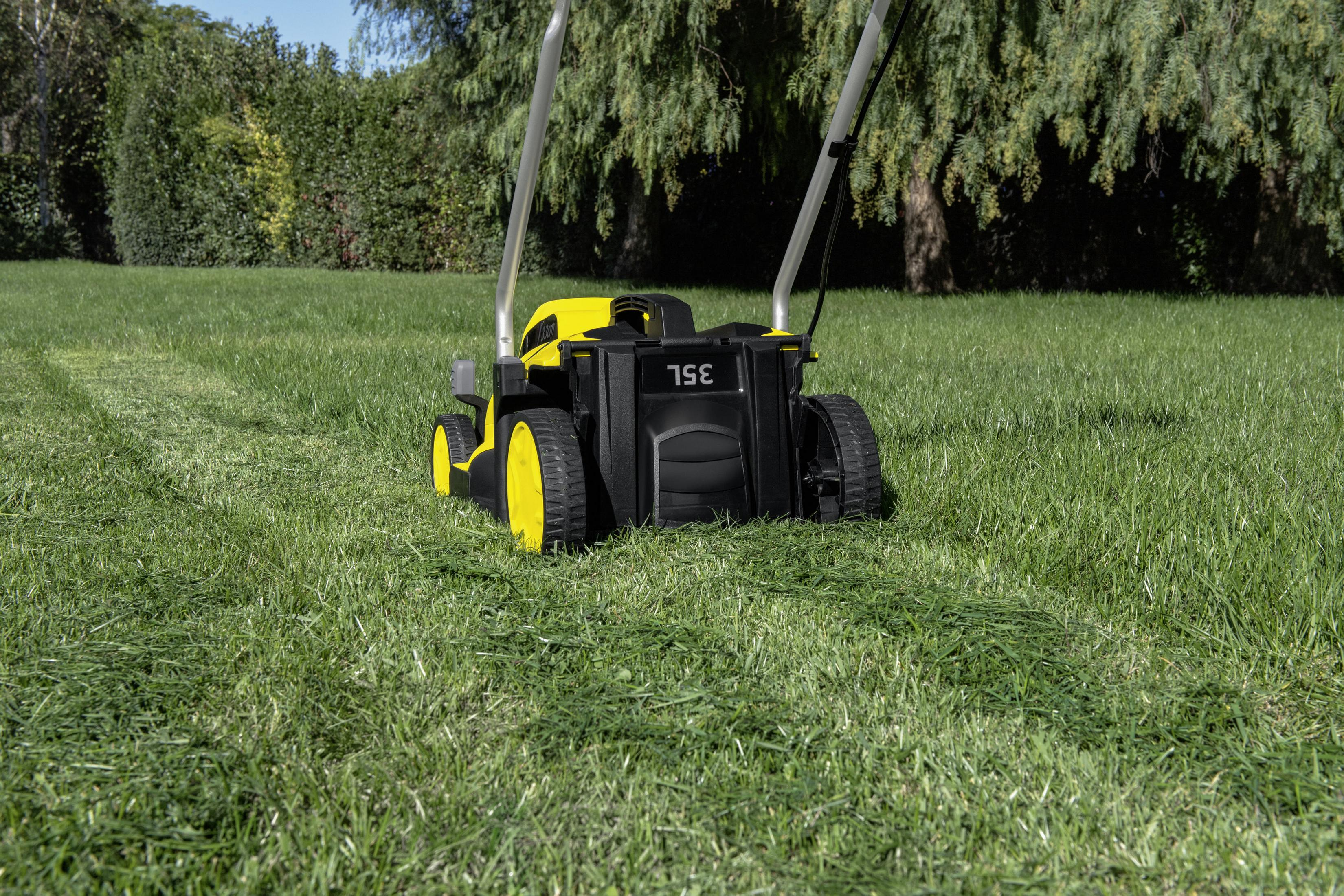 Ein gelb-schwarzer Rasenmäher schneidet Gras auf einem grünen Rasen. Der Mäher hat 35L Kapazität.