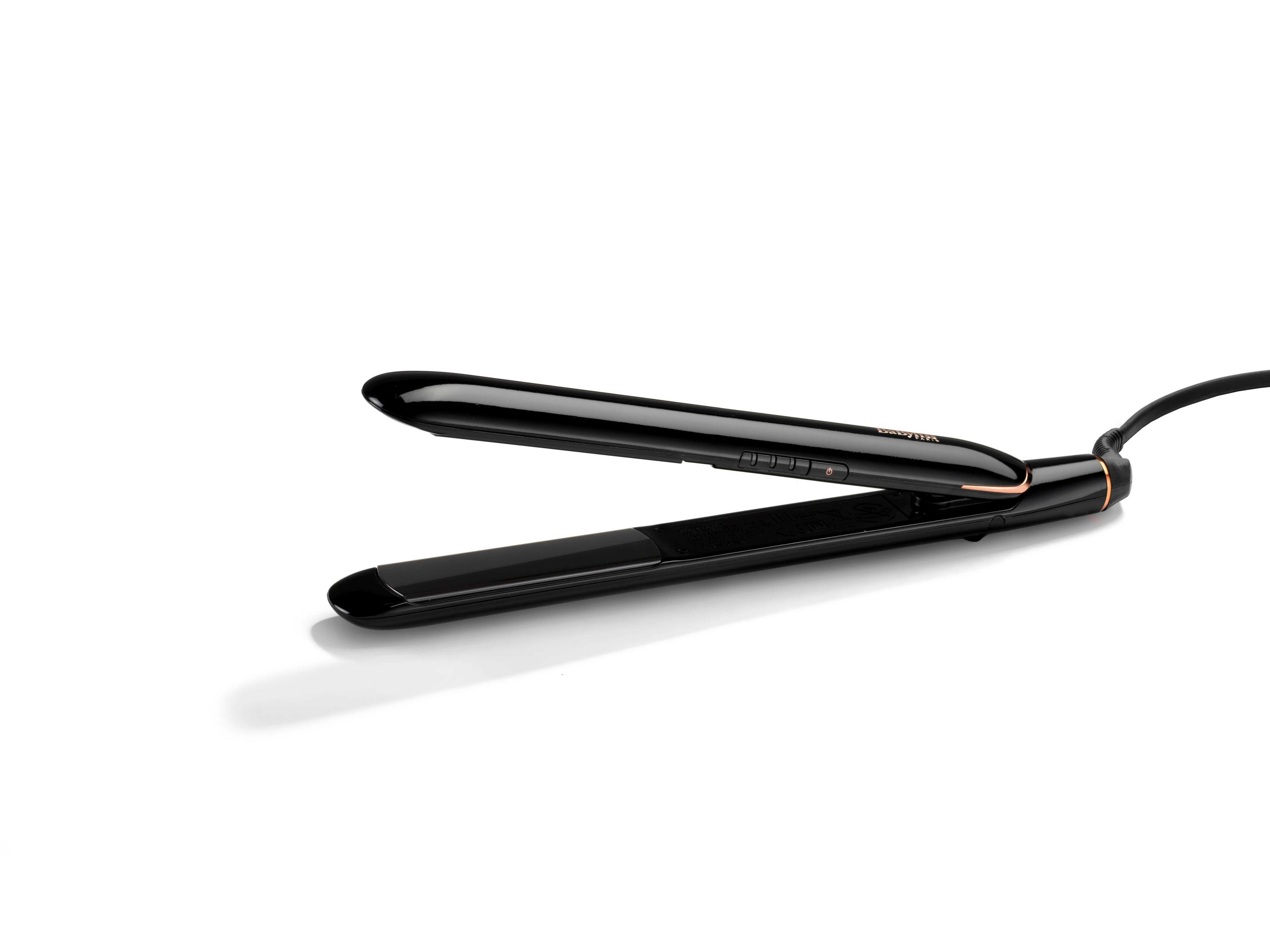 Czarna prostownica do włosów ze złotymi akcentami, otwarta i leżąca na białej powierzchni. Marka Babyliss.