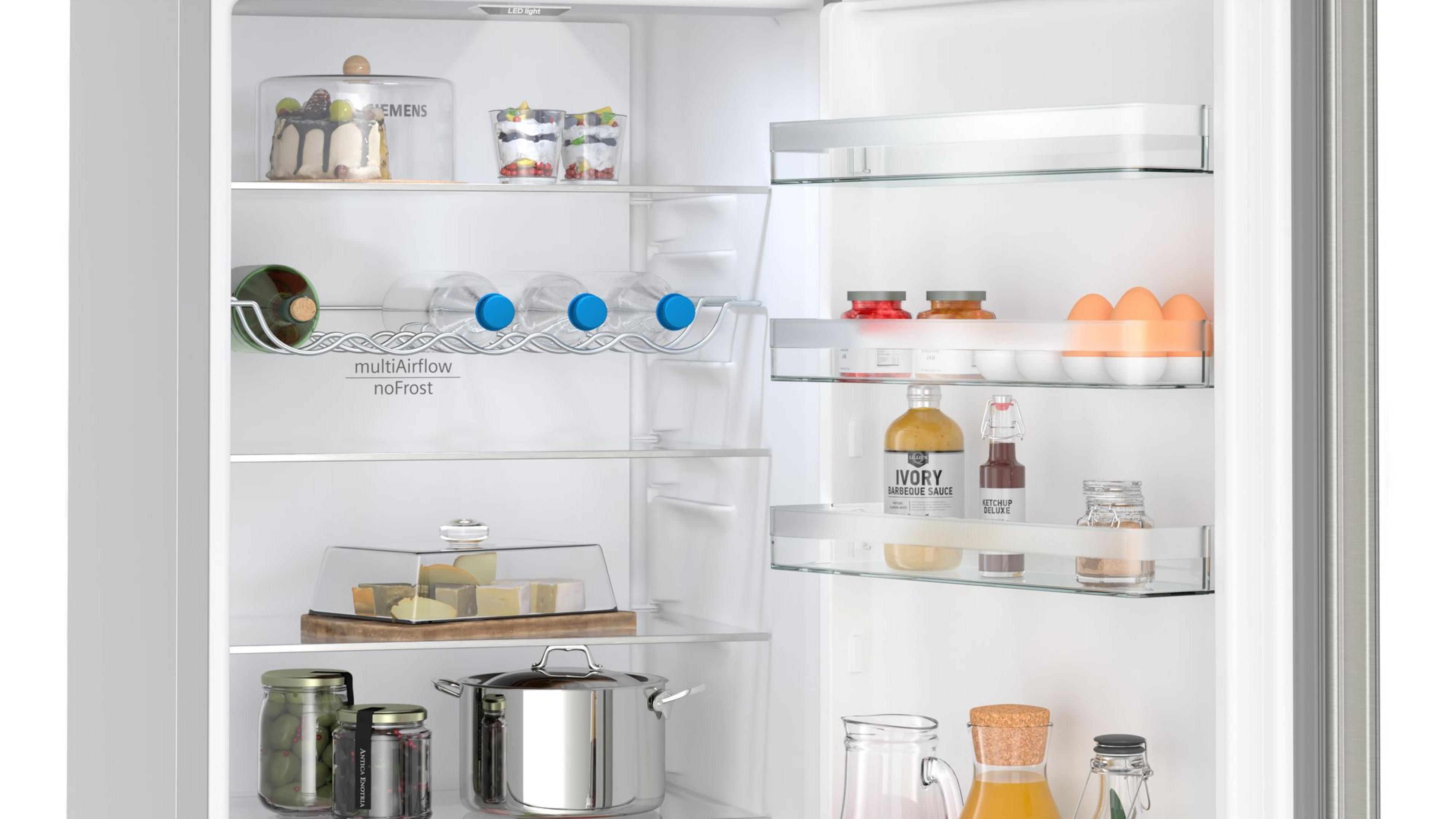 Interior de la nevera con alimentos en estantes. Incluye pastel, botellas y frascos.
