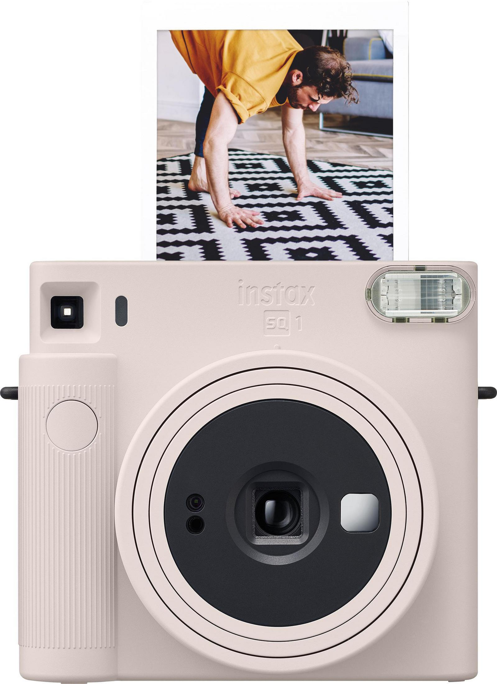 Pink instax camera with a photo. The photo shows a man doing yoga on a patterned mat.