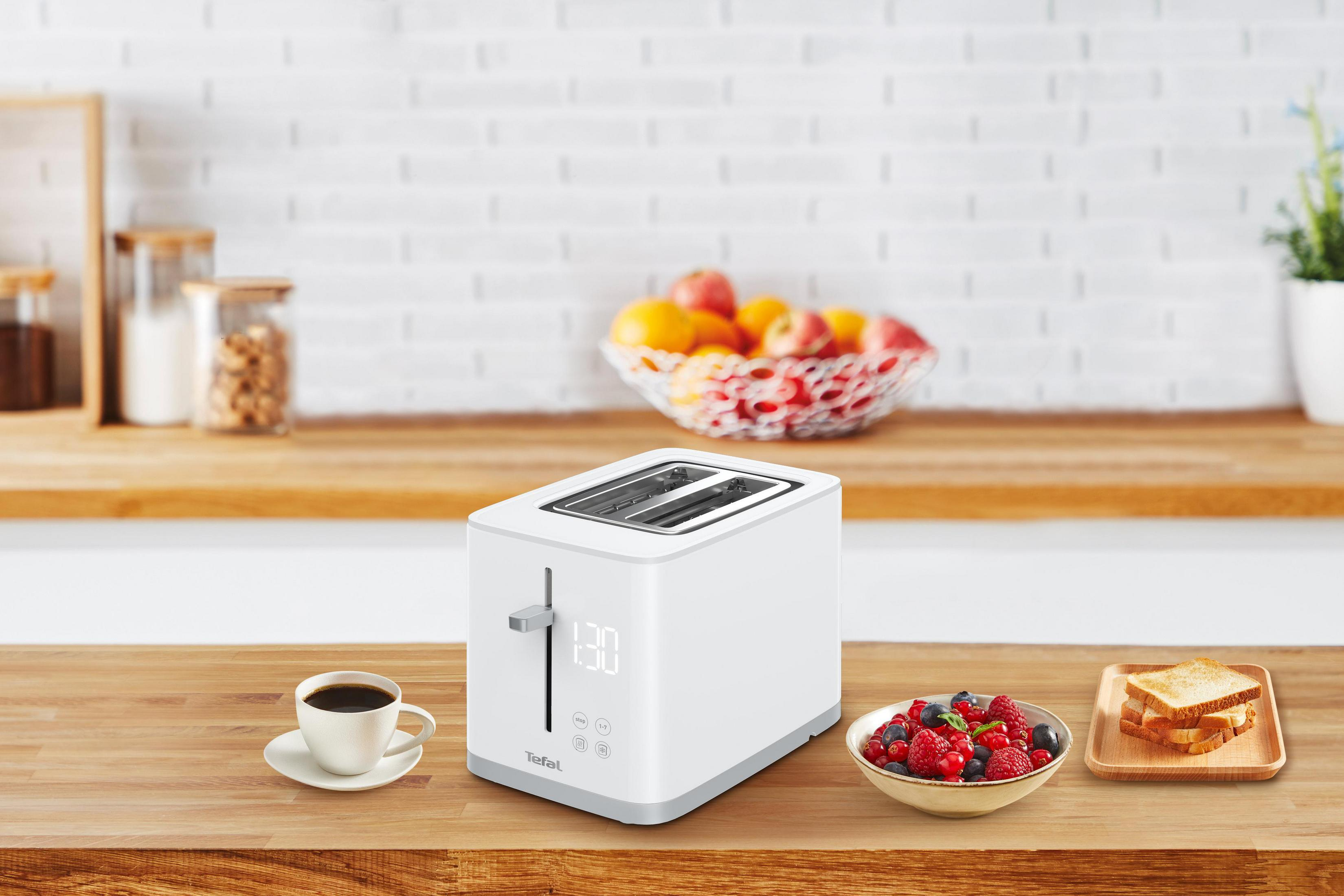 Weißer Toaster mit Digitalanzeige, Kaffee, Beeren und Toast auf einer Holz-Arbeitsplatte.