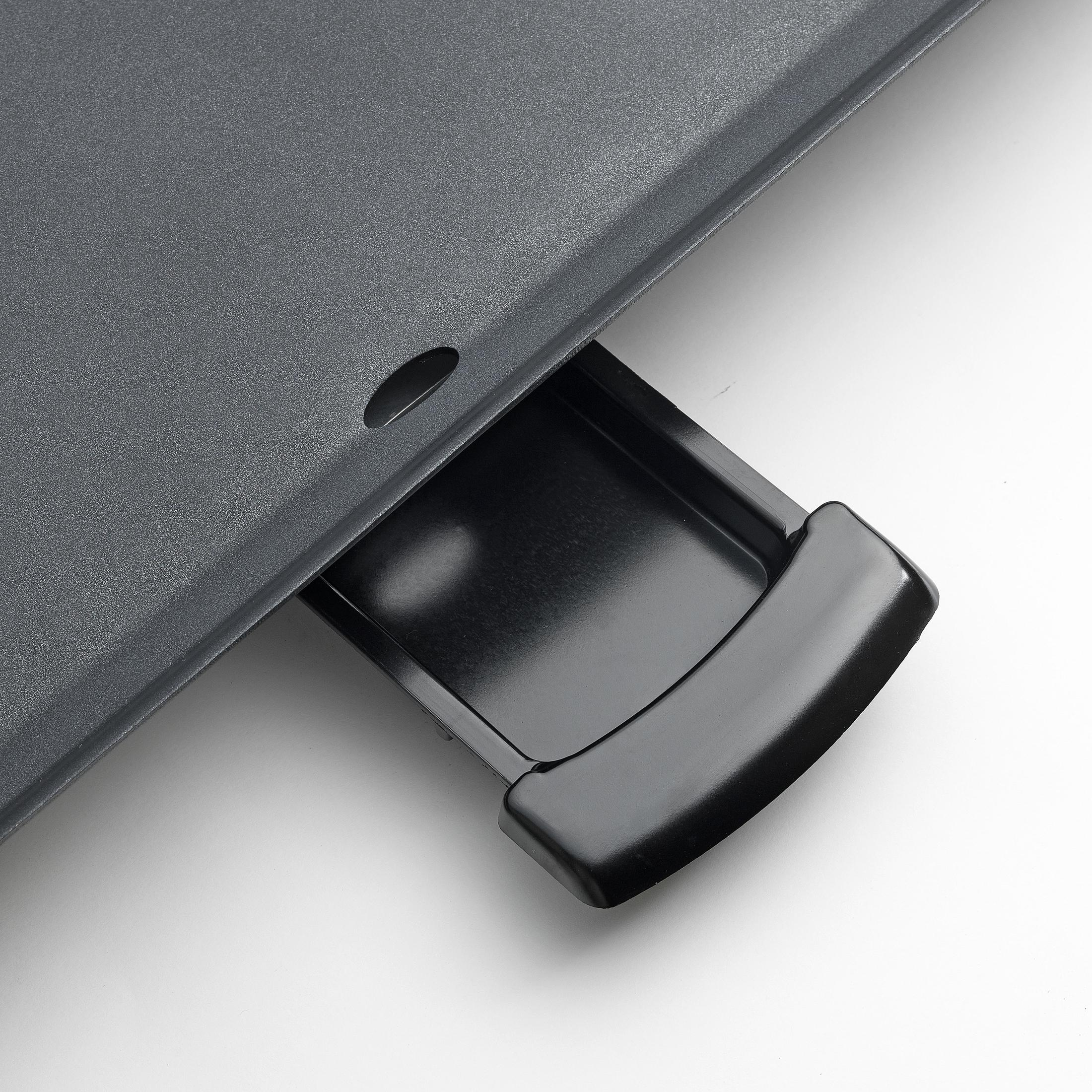 Un primo piano di un cassetto nero con una maniglia curva. È all'interno di una superficie grigia.