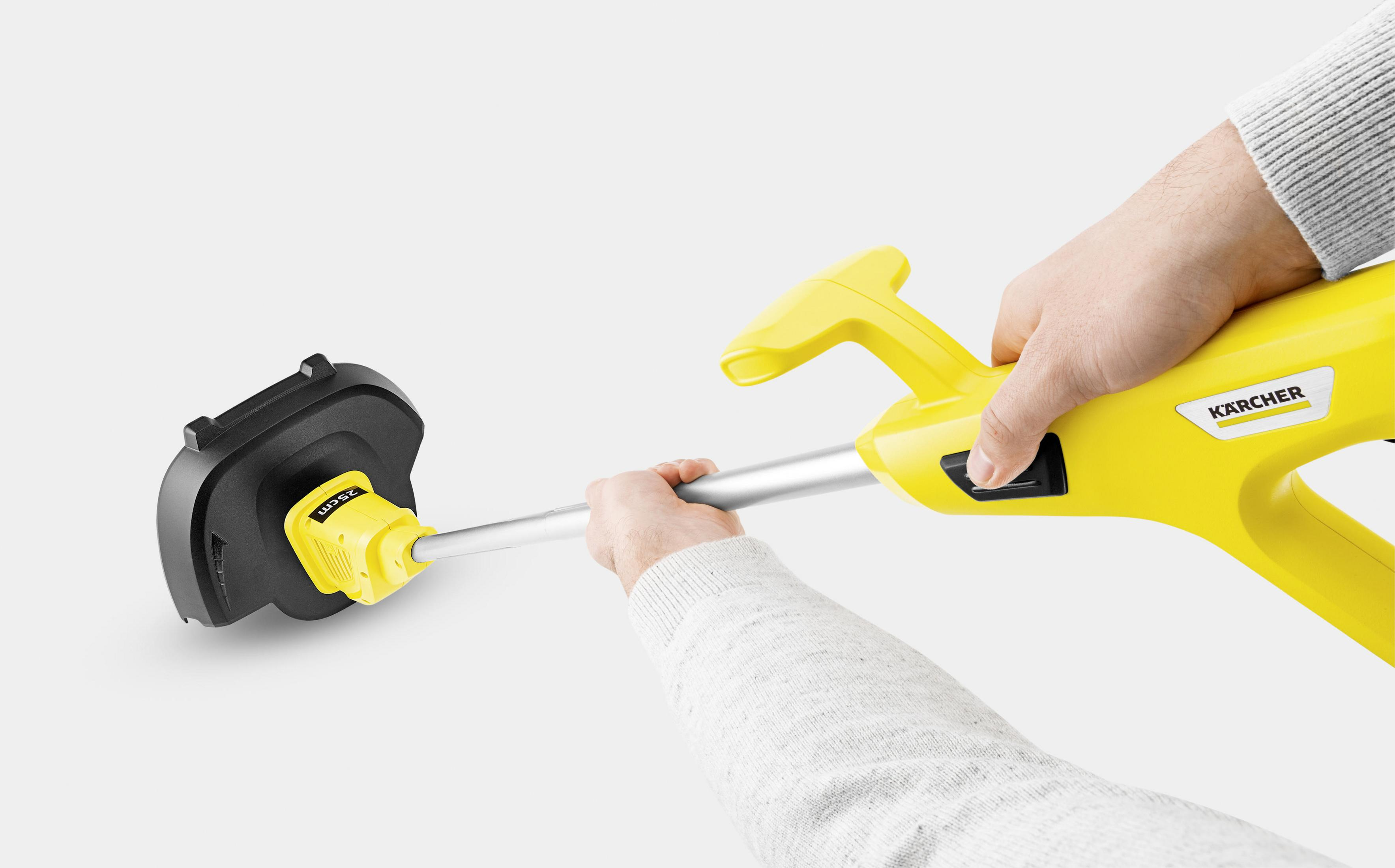 Recortadora Karcher amarilla sostenida por manos. Cabezal de corte negro. Fondo claro.