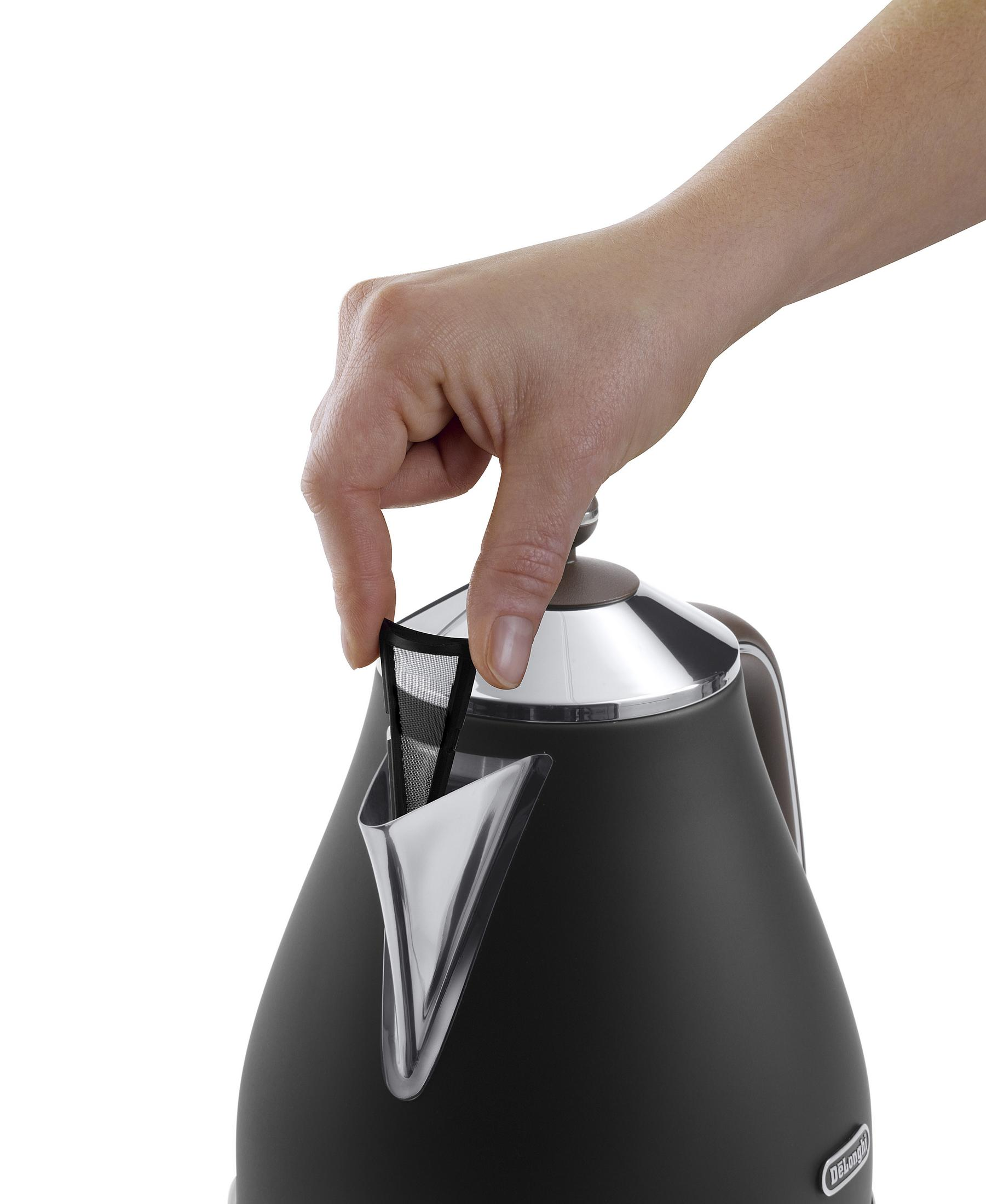 Dłoń wkładająca filtr do czarno-srebrnego czajnika elektrycznego.