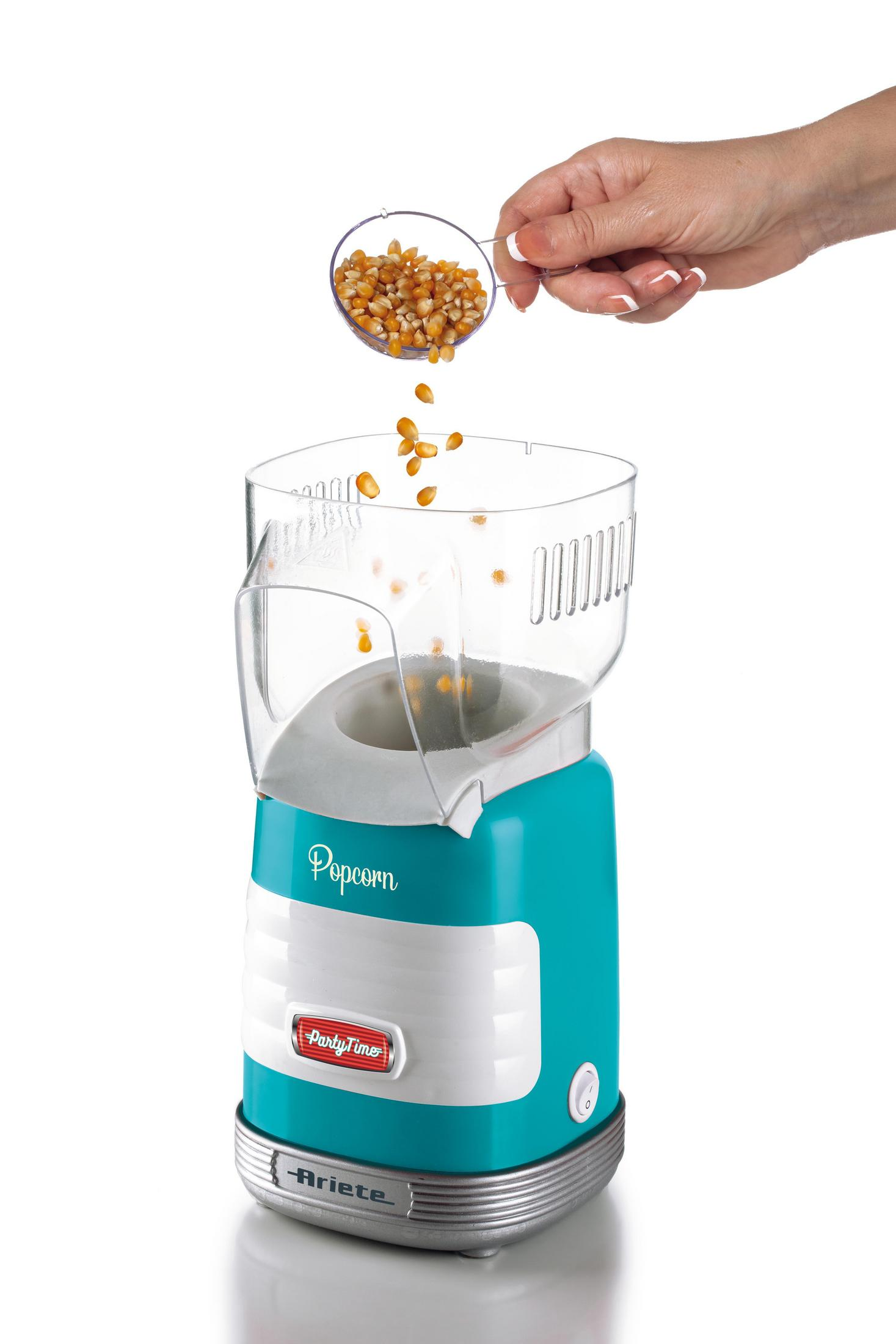 Niebieski automat do popcornu z ziarnami wsypywanymi przez rękę. Białe tło. Widoczne słowo „Popcorn”.